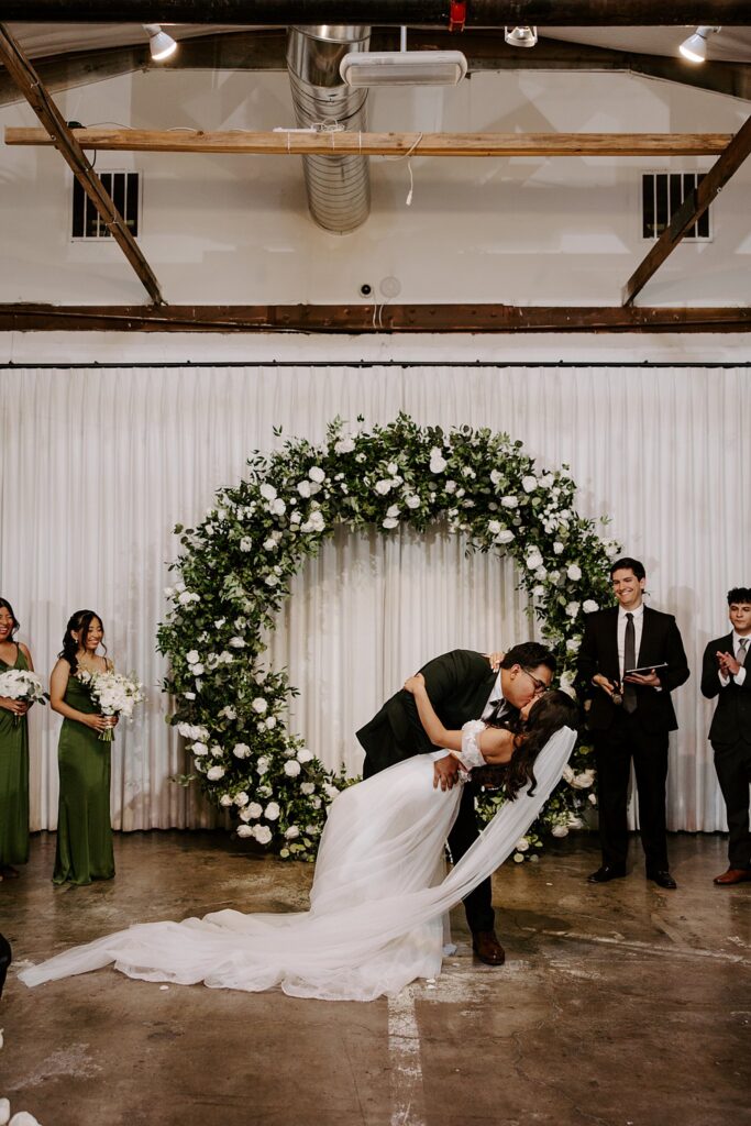 groom dips bride for first kiss at ceremony by Katelyn Faye Photography