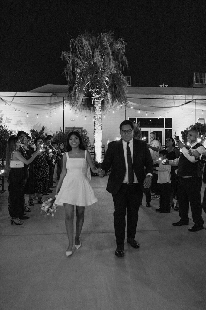 newlyweds leave their wedding as guests hold sparklers by Katelyn Faye Photography