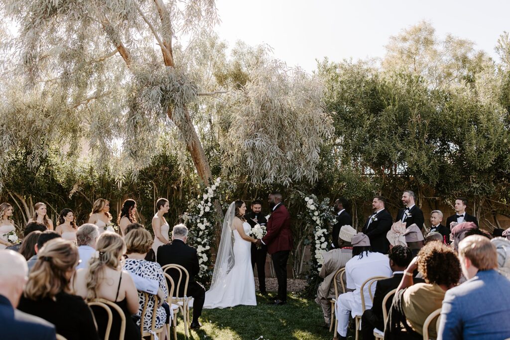 bride and groom hold hands at altar during ceremony by Katelyn Faye Photography