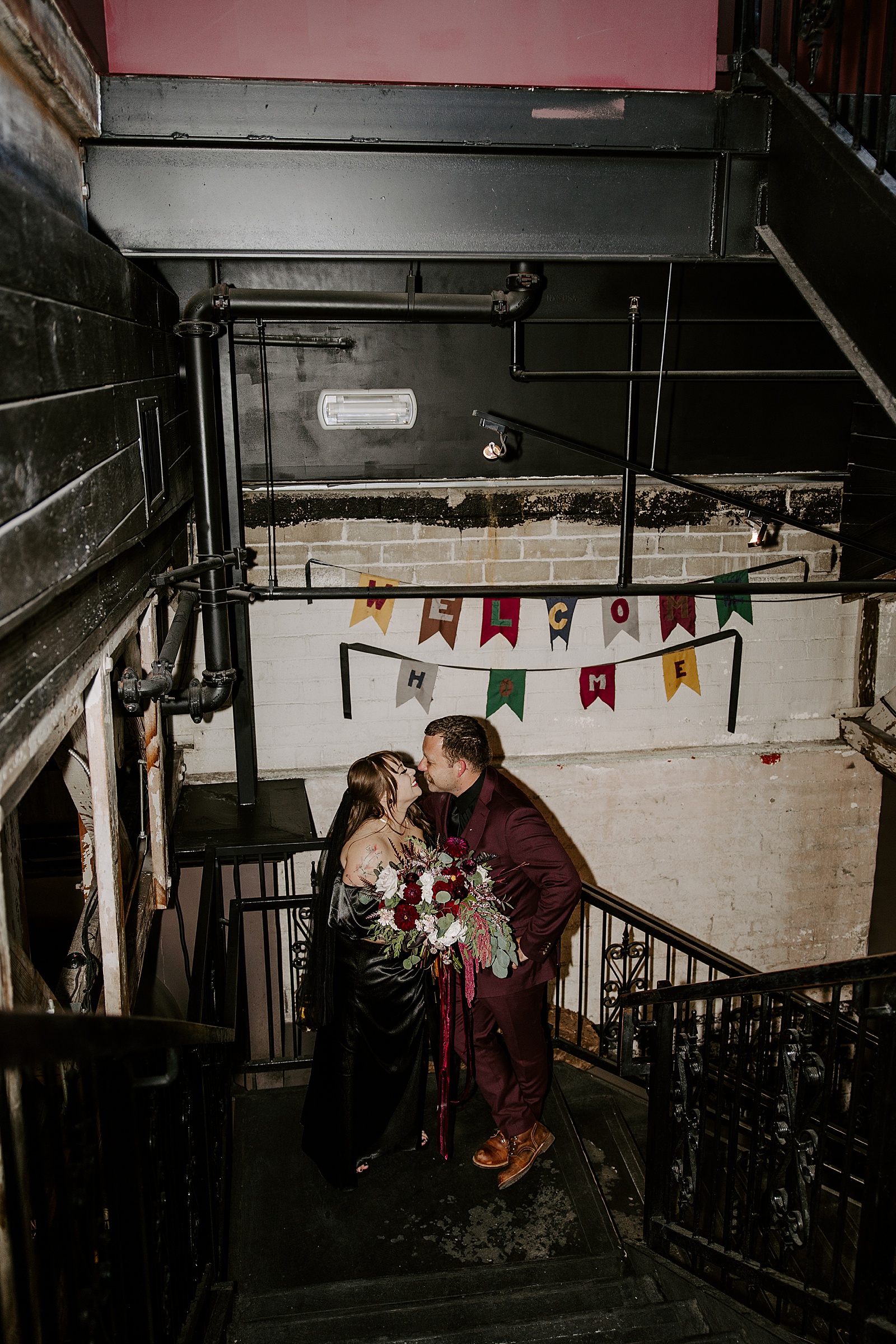 man and woman kiss in stairwell under flags after Commonwealth Ceremony