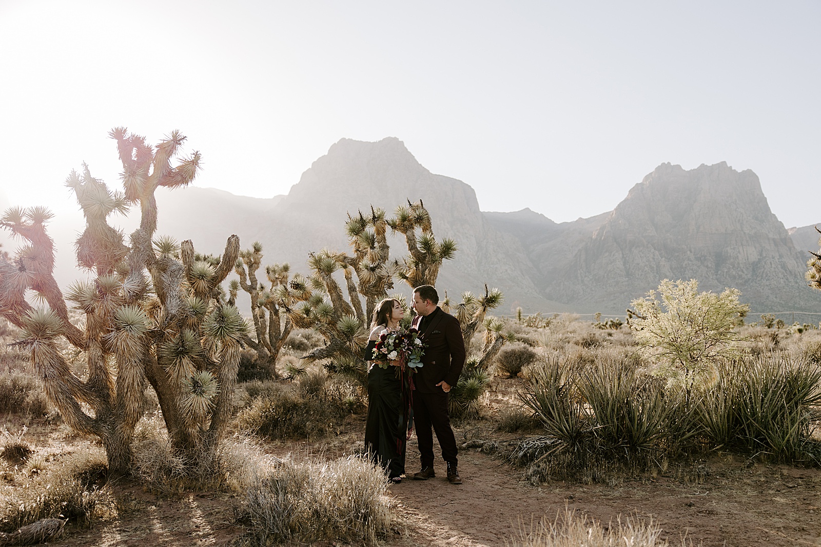 bride in black dress holds flowers in desert  by Las Vegas Elopement Photographer