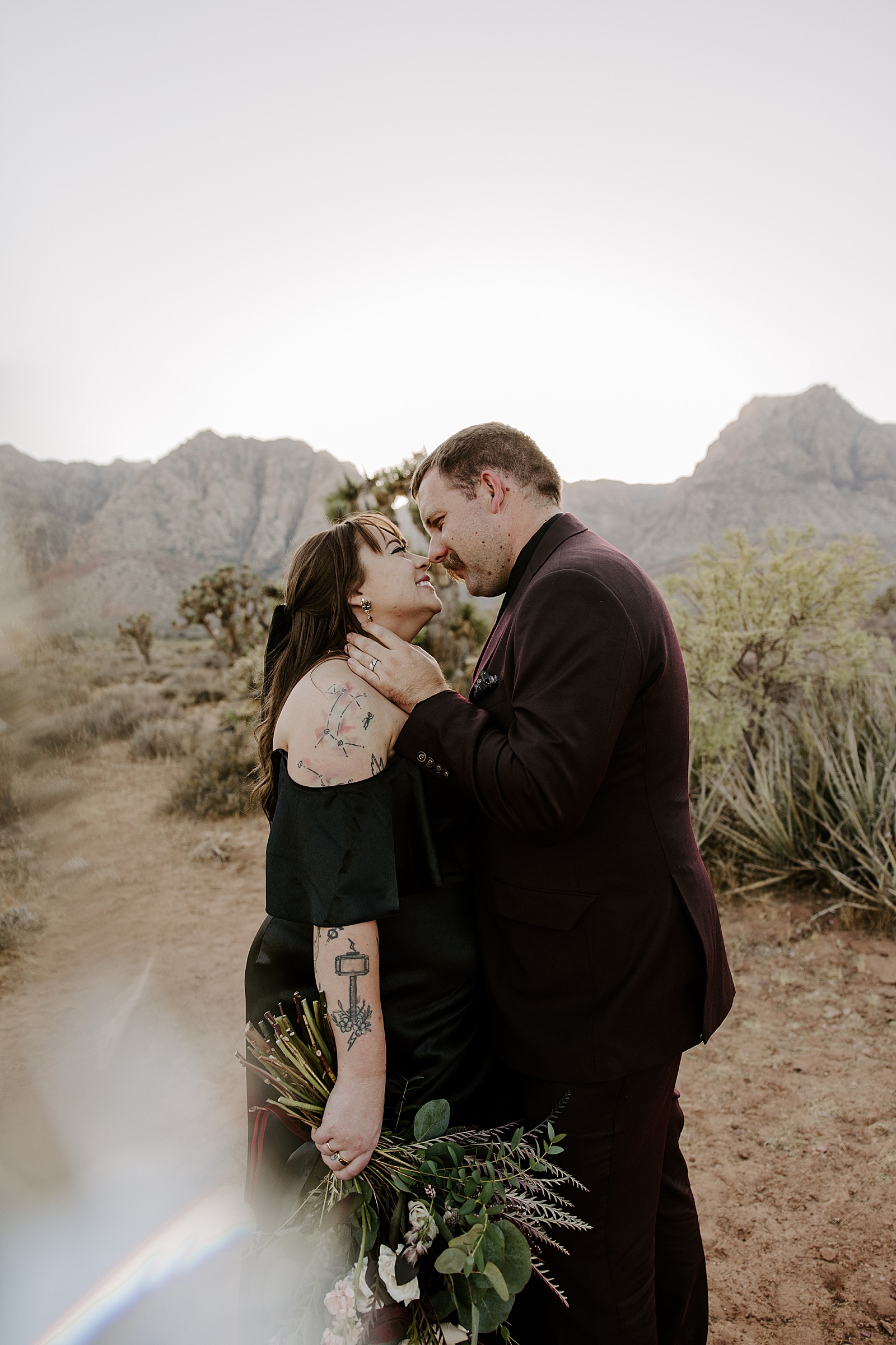 newlyweds touch noses and smile in the desert by Las Vegas Elopement Photographer