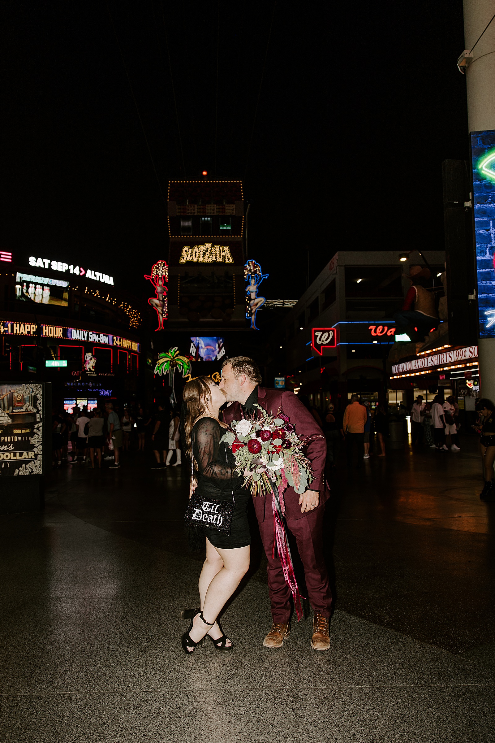 man kisses wife under nightlife flashing signs by Katelyn Faye Photography 