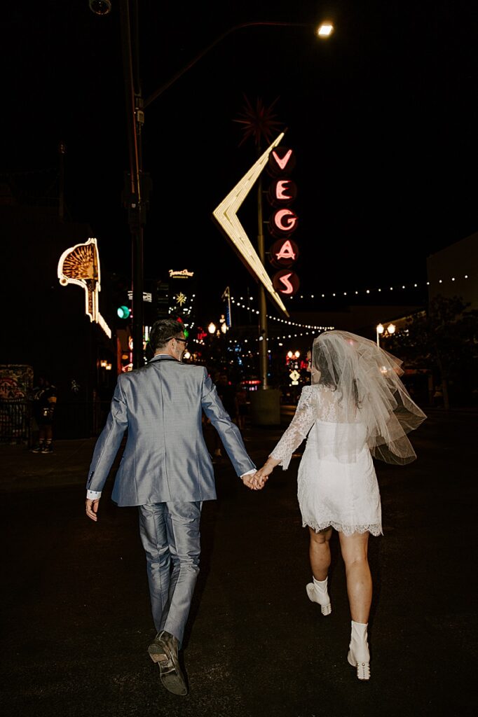 bride and groom running down street at night by Las Vegas wedding photographer