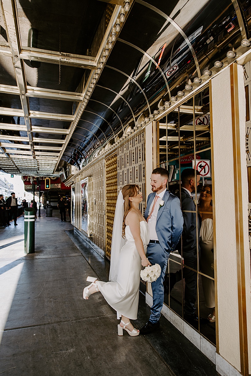 Newlyweds lean on gold wall by Katelyn Faye Photo