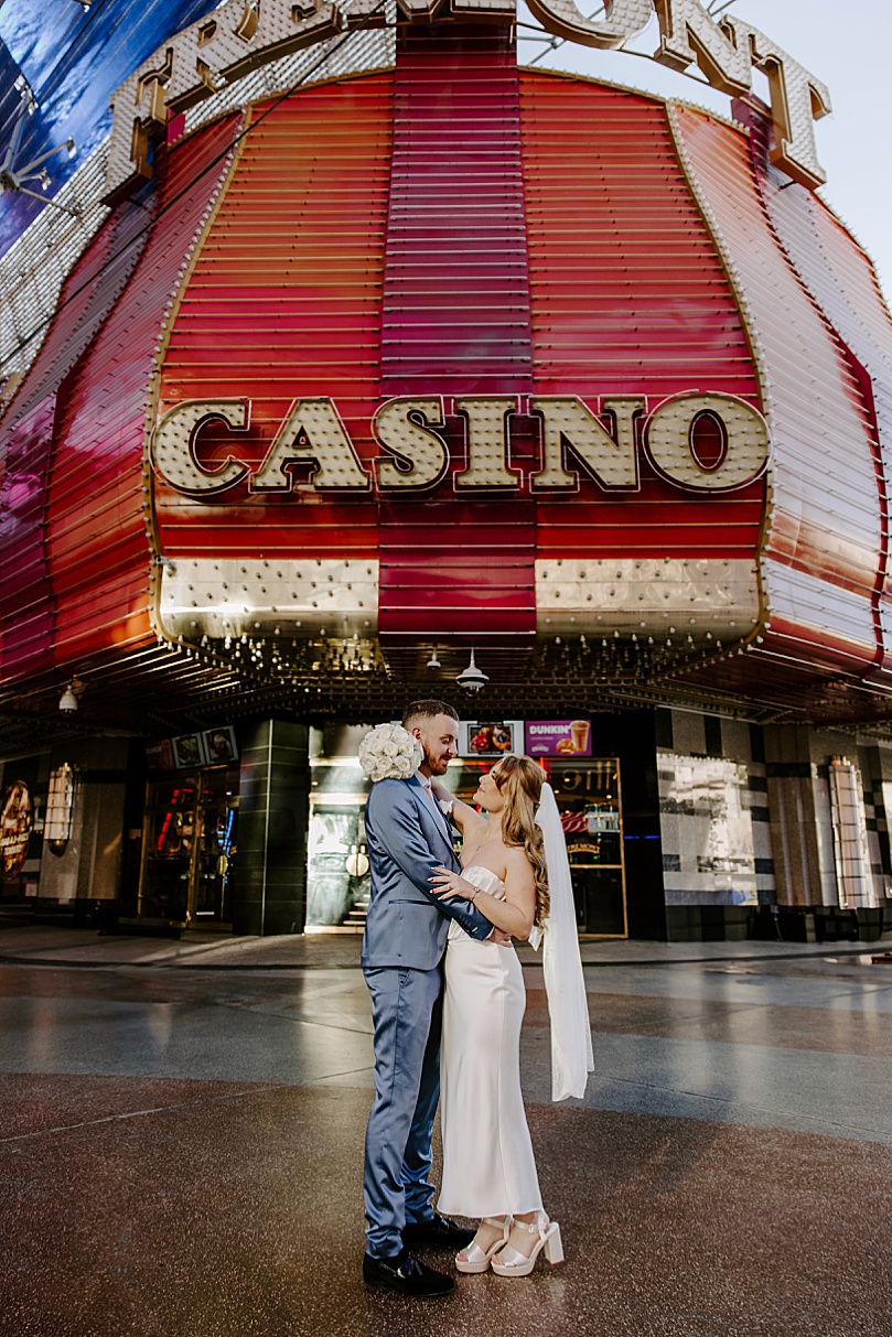 bride and groom embrace under casino sign by Katelyn Faye Photo