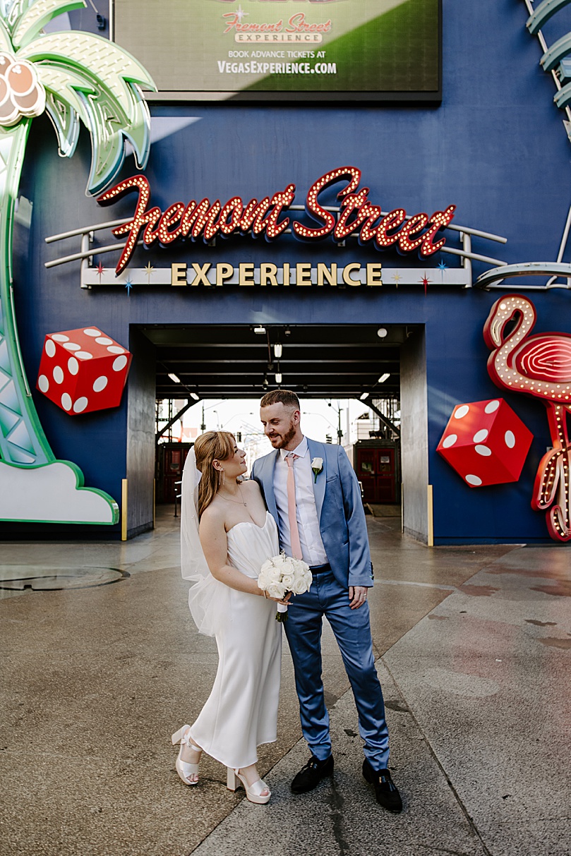 man in blue suit looks at bride by Fremont street sign by Katelyn Faye Photo