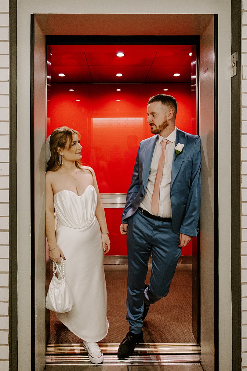 man and woman stand in elevator door by Las Vegas wedding photographer