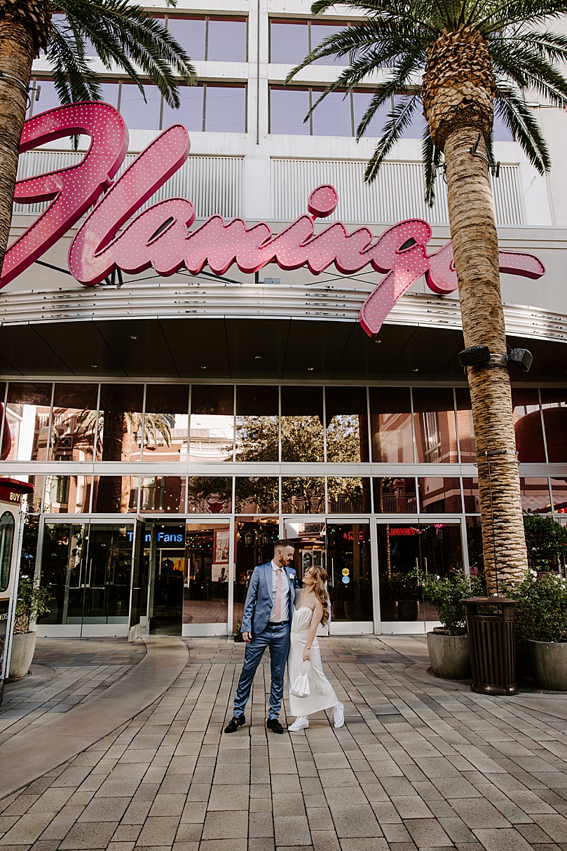 bride and groom look at each other under Flamingo sign by Las Vegas wedding photographer