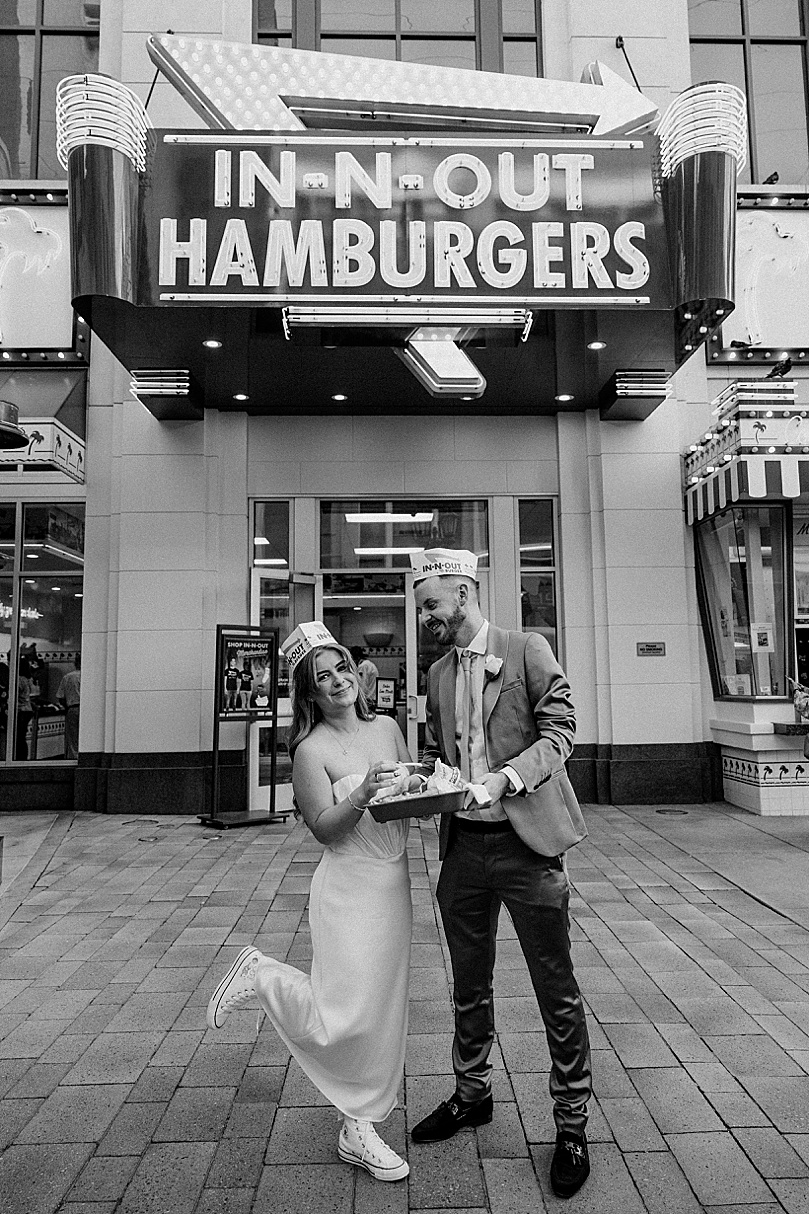 bride kicks up foot while eating burger on sidewalk by Katelyn Faye Photo