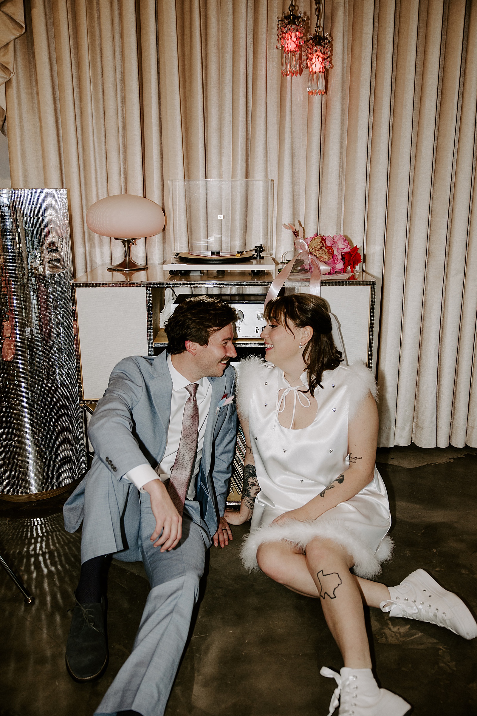 bride and groom sit on floor at Sure Thing Chapel for retro inspired elopement