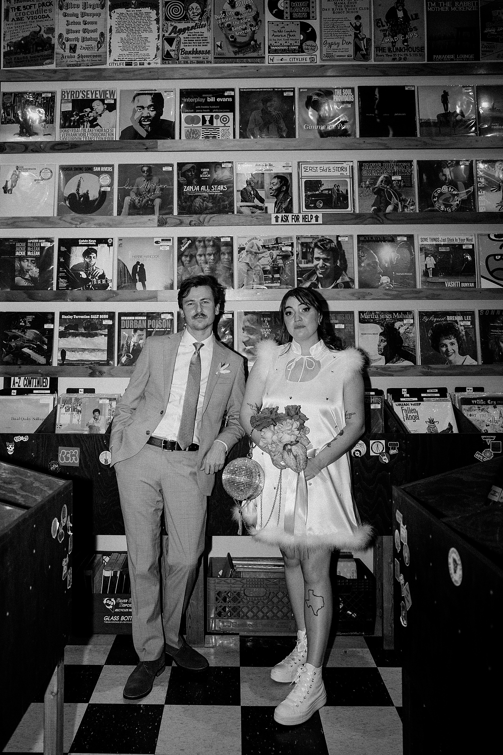 husband and wife stand in front of wall of records by Las Vegas Wedding Photographer