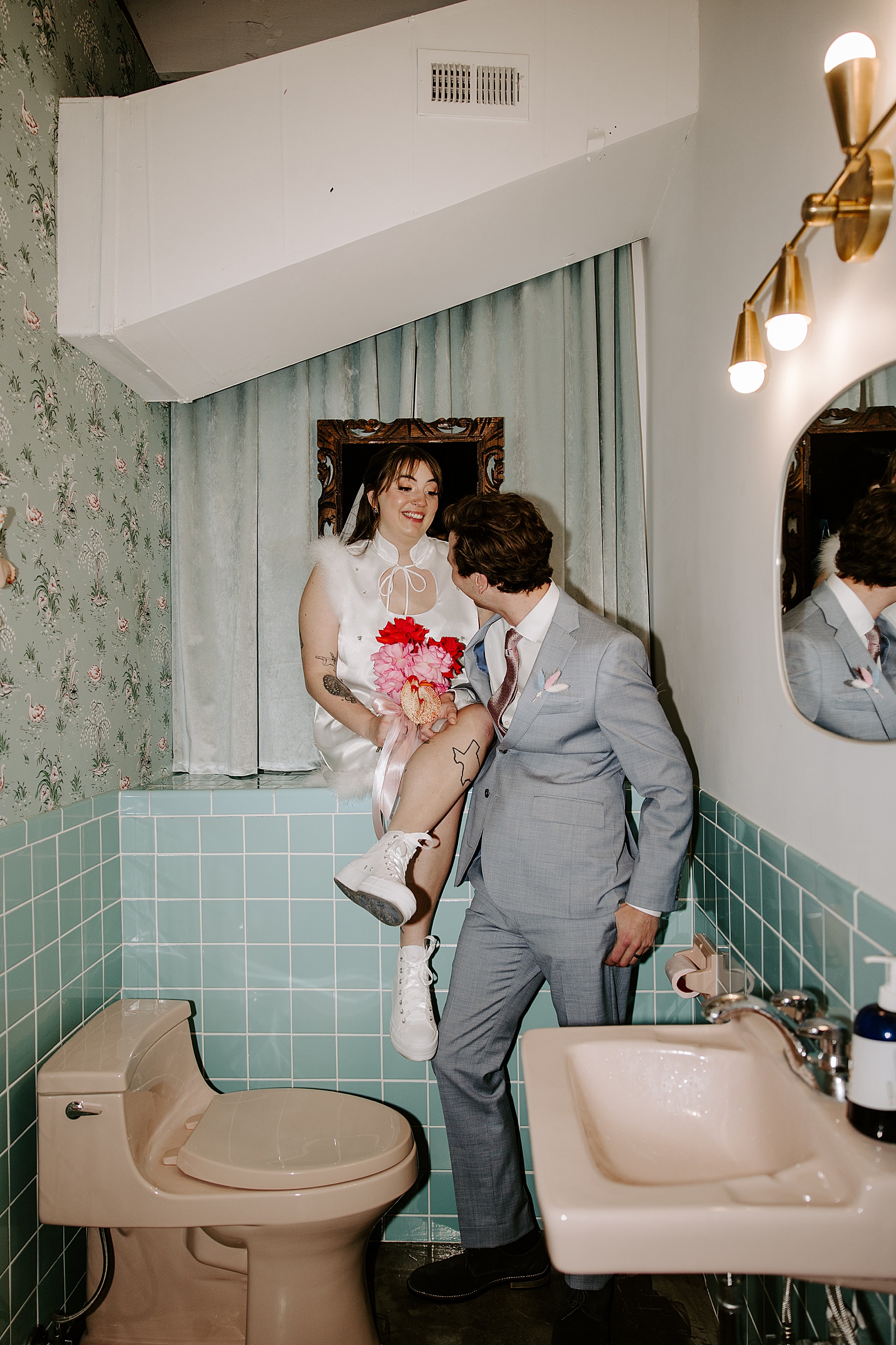 woman in white dress sits on teal counter next to man by Katelyn Faye Photo