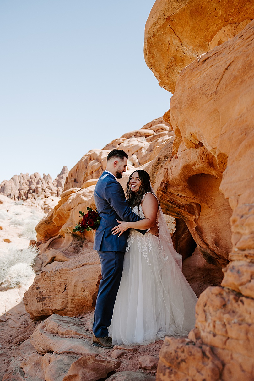 man embraces new wife on red rocks by Las Vegas Elopement Photographer