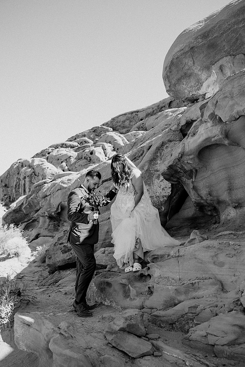 husband helps wife down rocks at Valley of Fire elopement