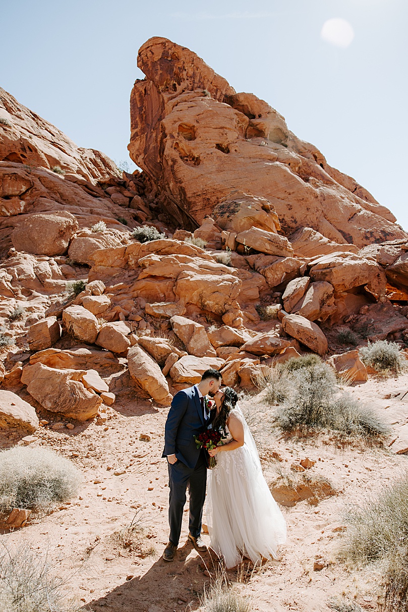 bride and groom kiss under red rocks by Katelyn Faye Photo