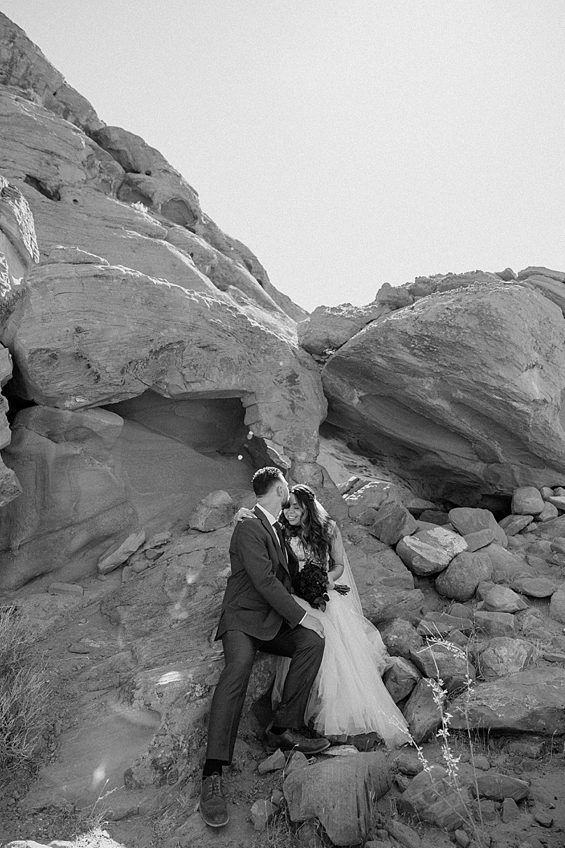 man kisses his new wife while sitting on rocks at Valley of Fire elopement