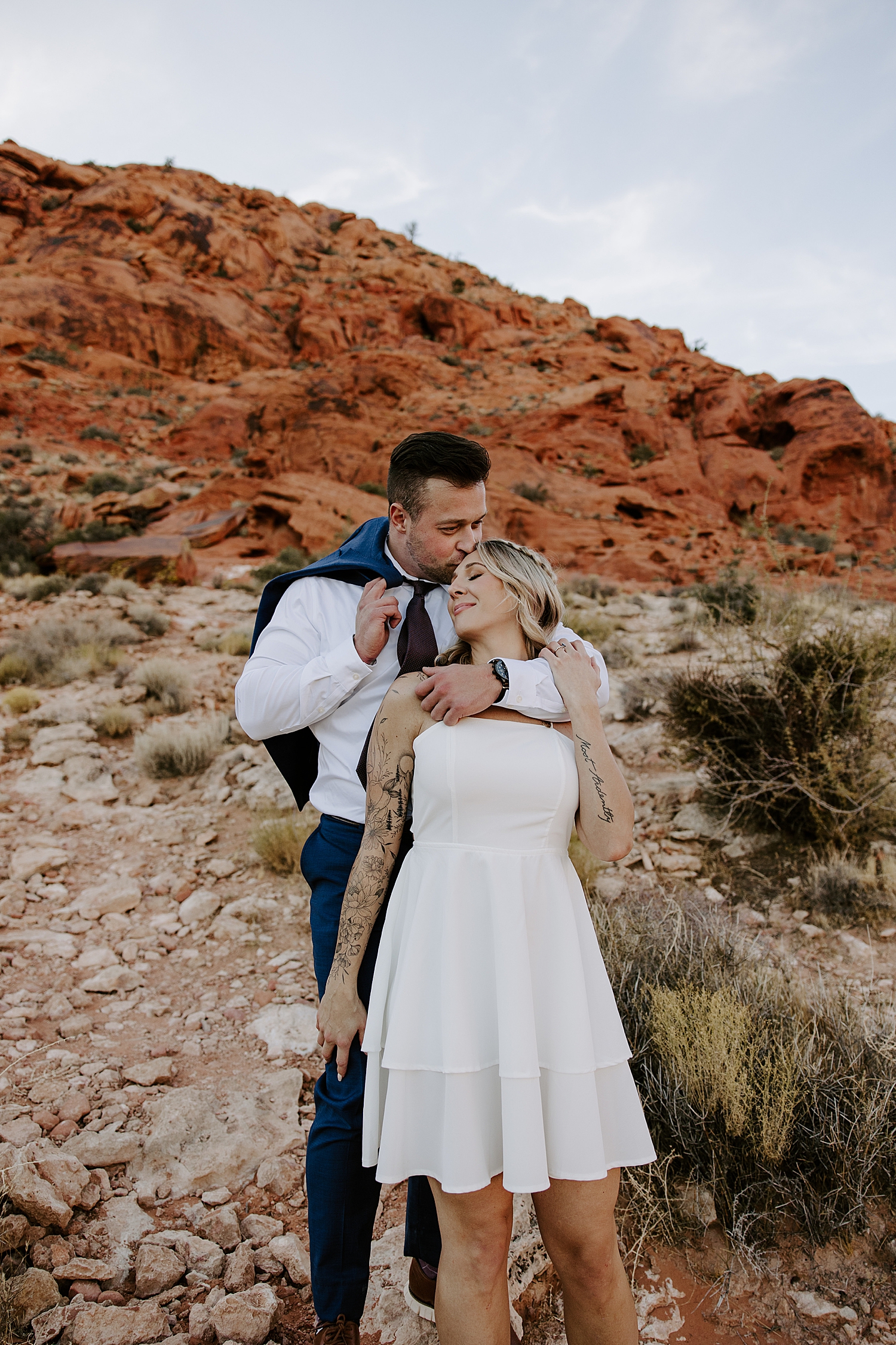 woman in white dress leans agains her fiancé by Las Vegas Wedding Photographer