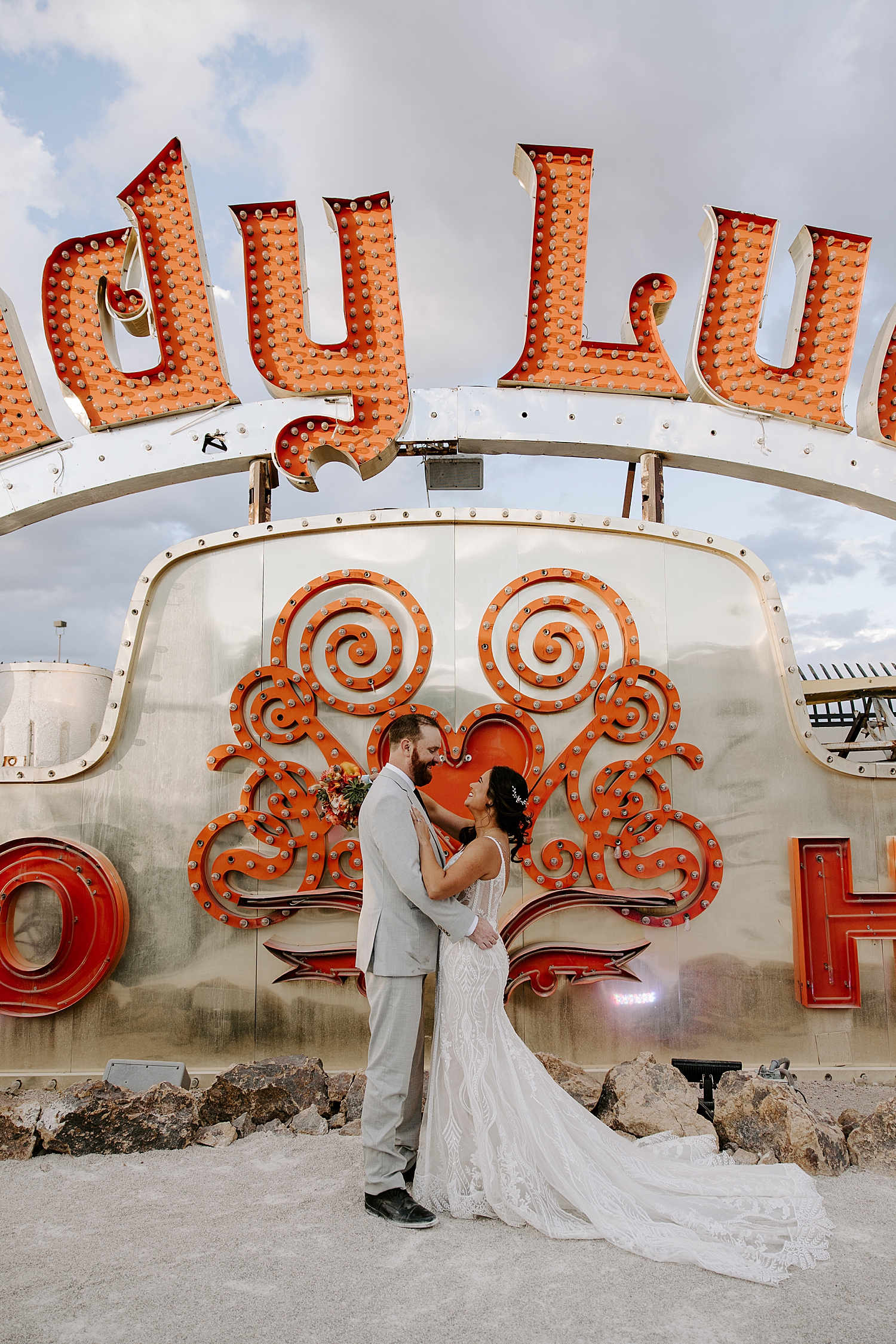 newlyweds embrace in front of big sign at Neon Museum Ceremony