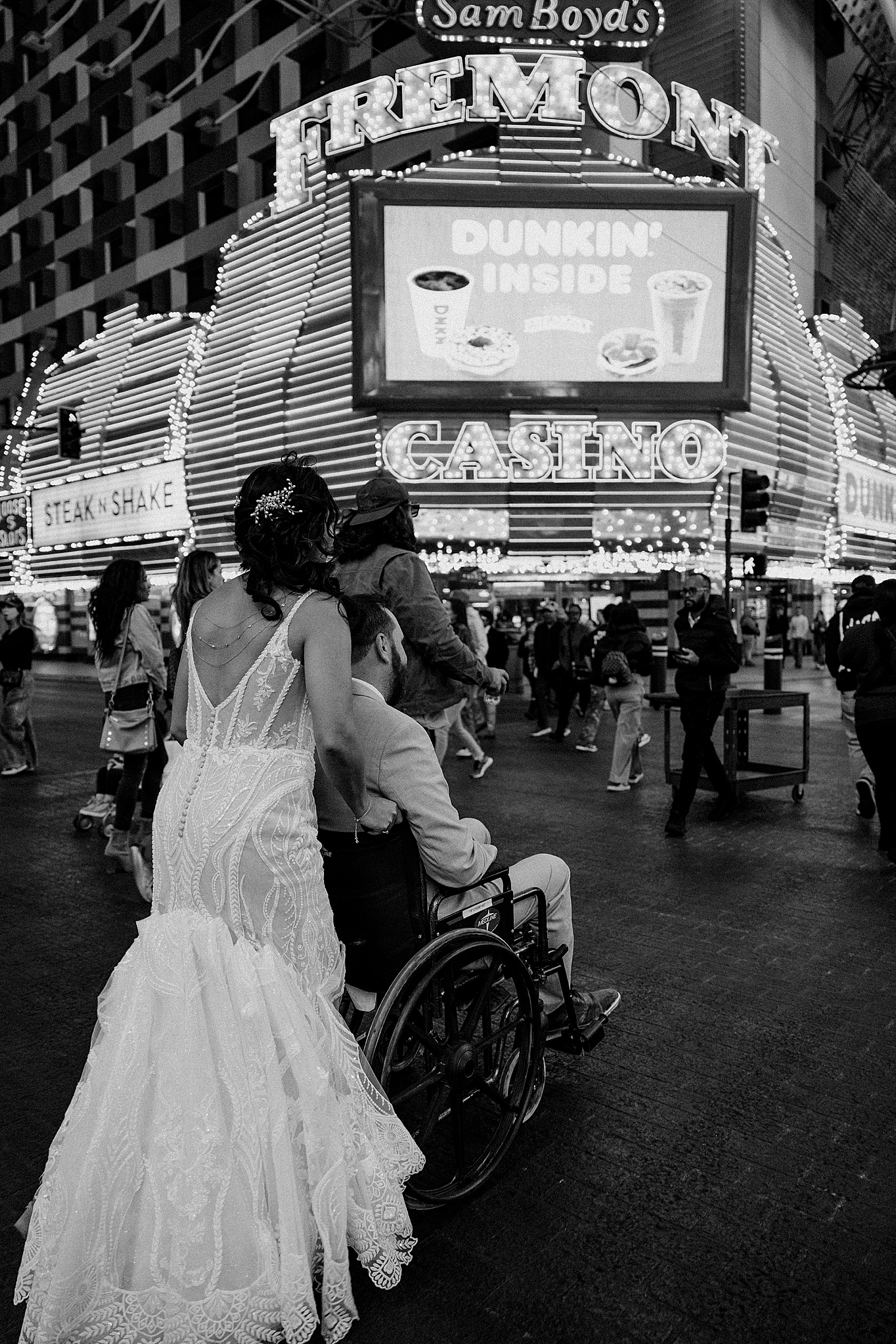 bride pushes grooms wheelchair down Fremont street by Katelyn Faye Photo 