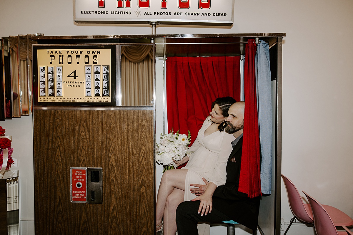 couple takes wedding photos in a photobooth at Sure Thing Chapel