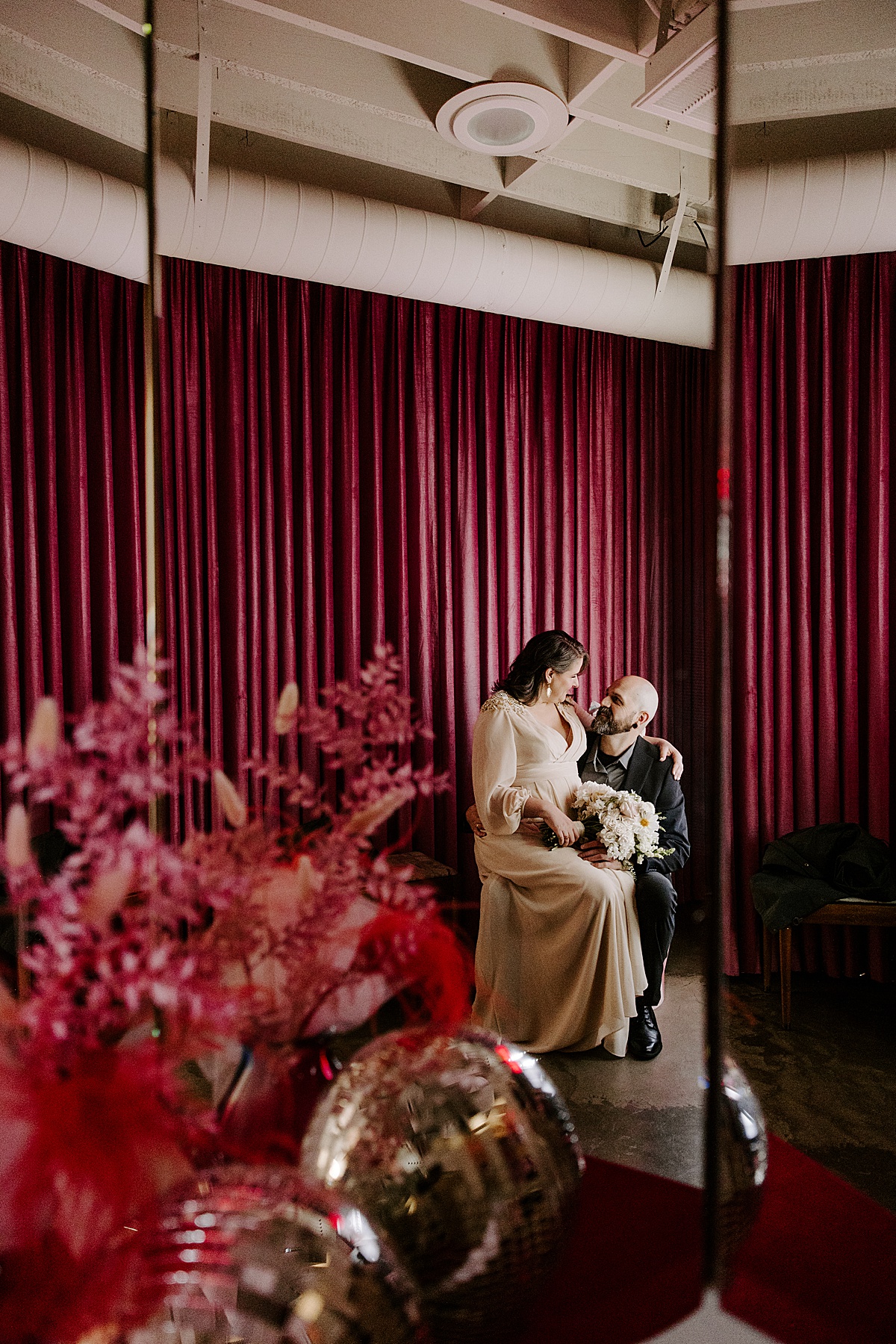 bride sits on grooms lap at venue by katelyn faye photography