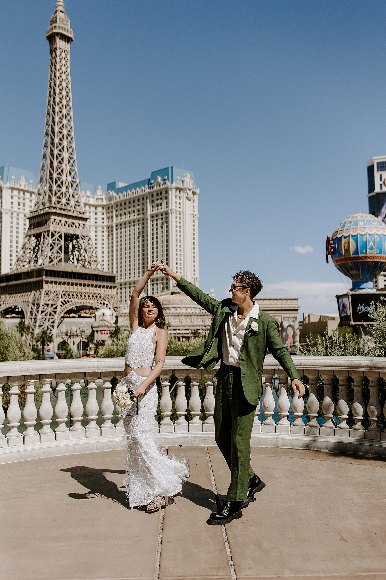 man in green suit spins his wife on sidewalk by Las Vegas wedding photographer