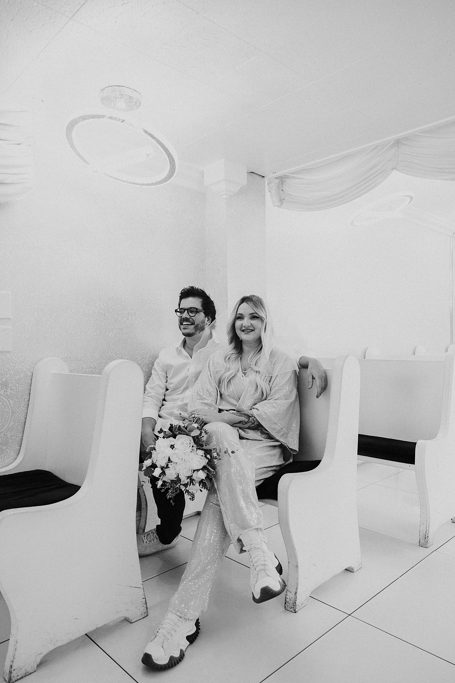bride and groom sit in pew by Katelyn Faye Photo
