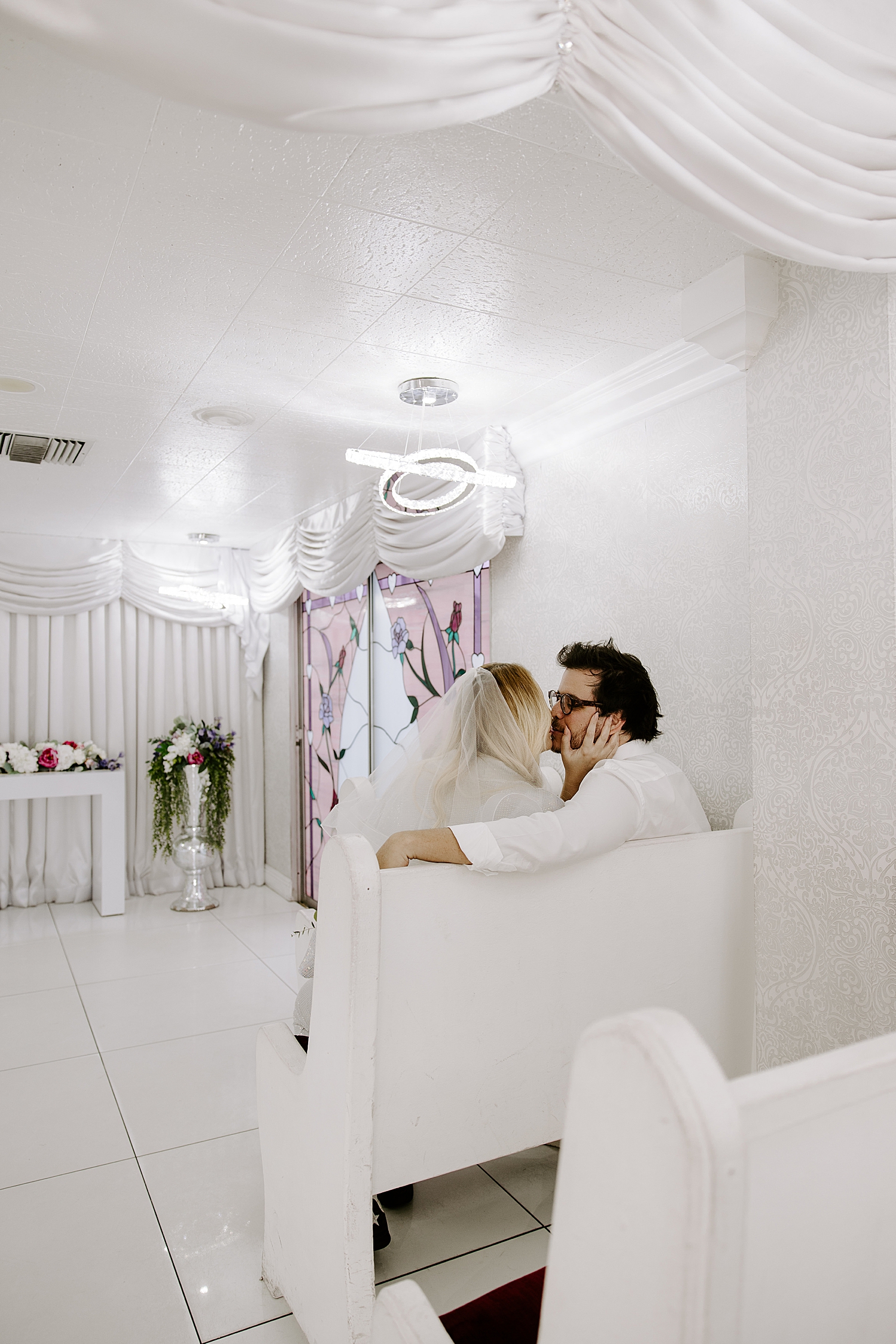 man and woman kiss in pew by Las Vegas wedding photographer