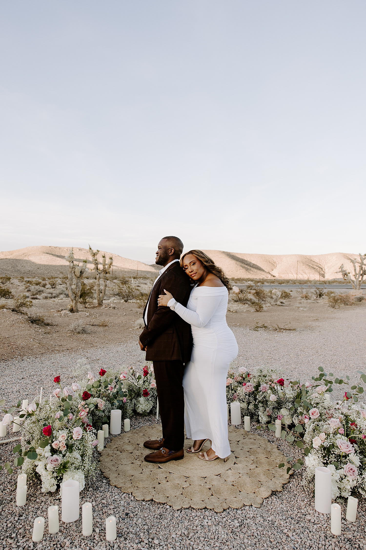 woman hugs her man in ring of flowers for desert surprise proposal
