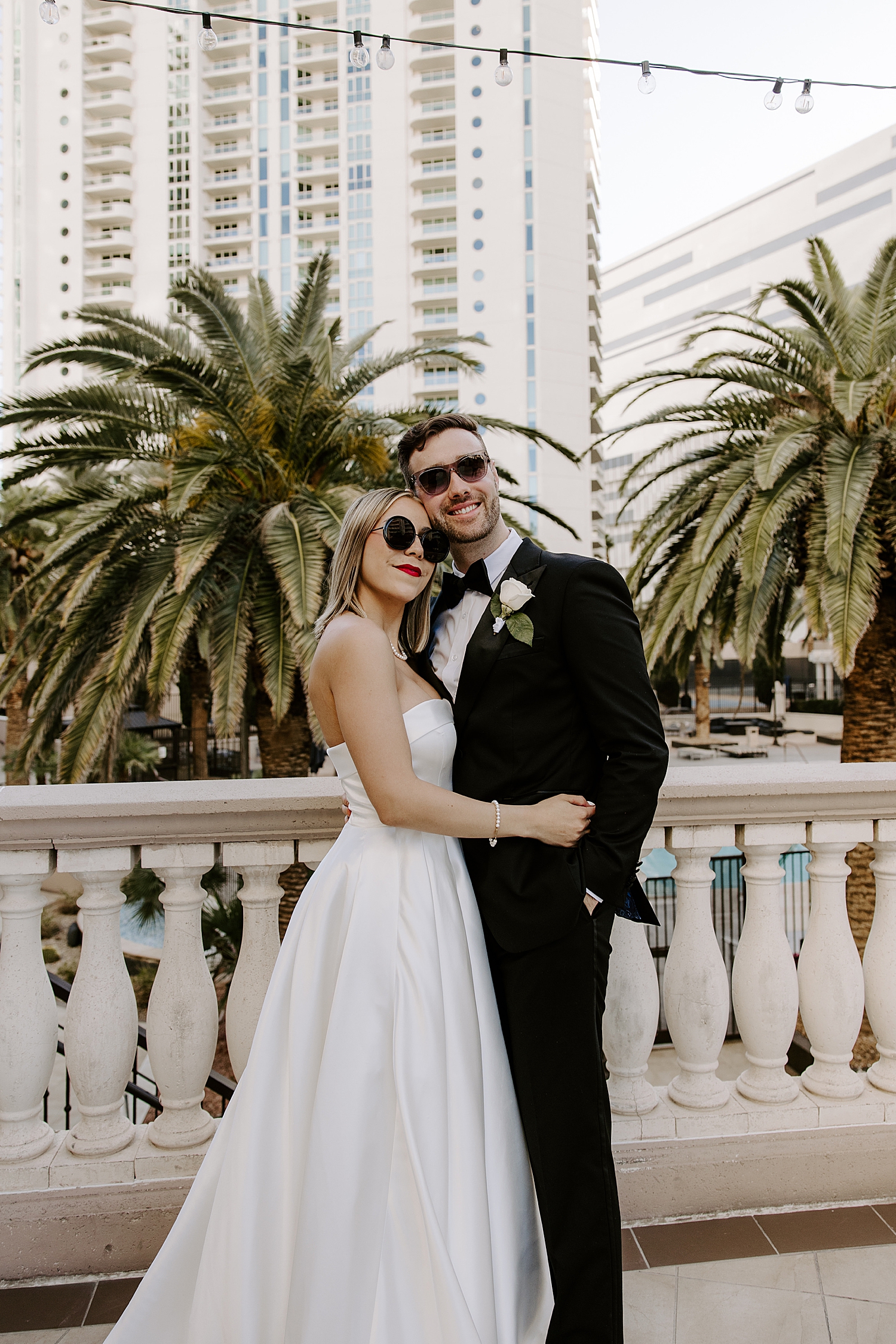 newlyweds wear big sunglasses in front of palm trees by Las vegas wedding photographer