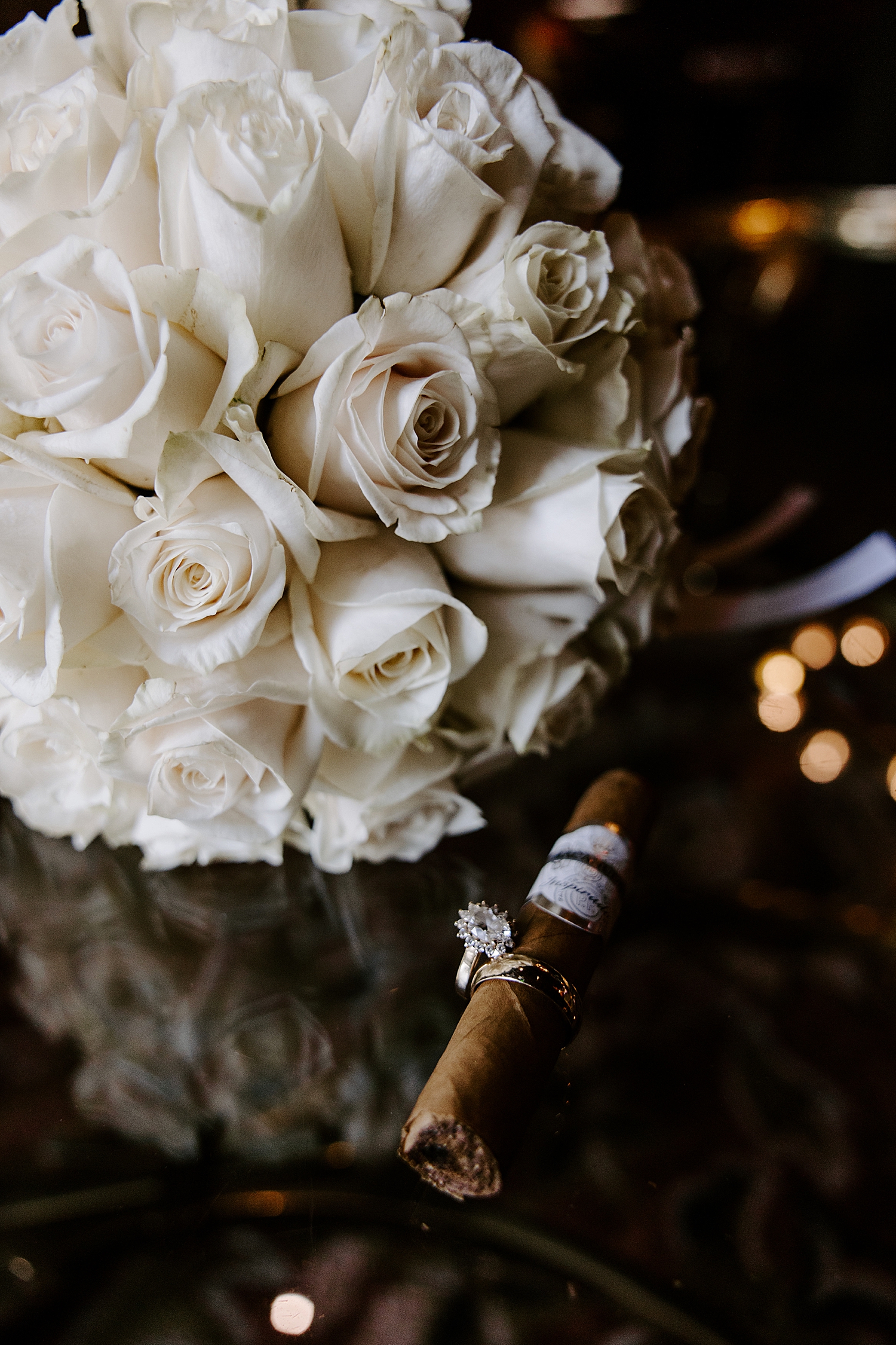 rings on cigar next to white roses by Las vegas wedding photographer