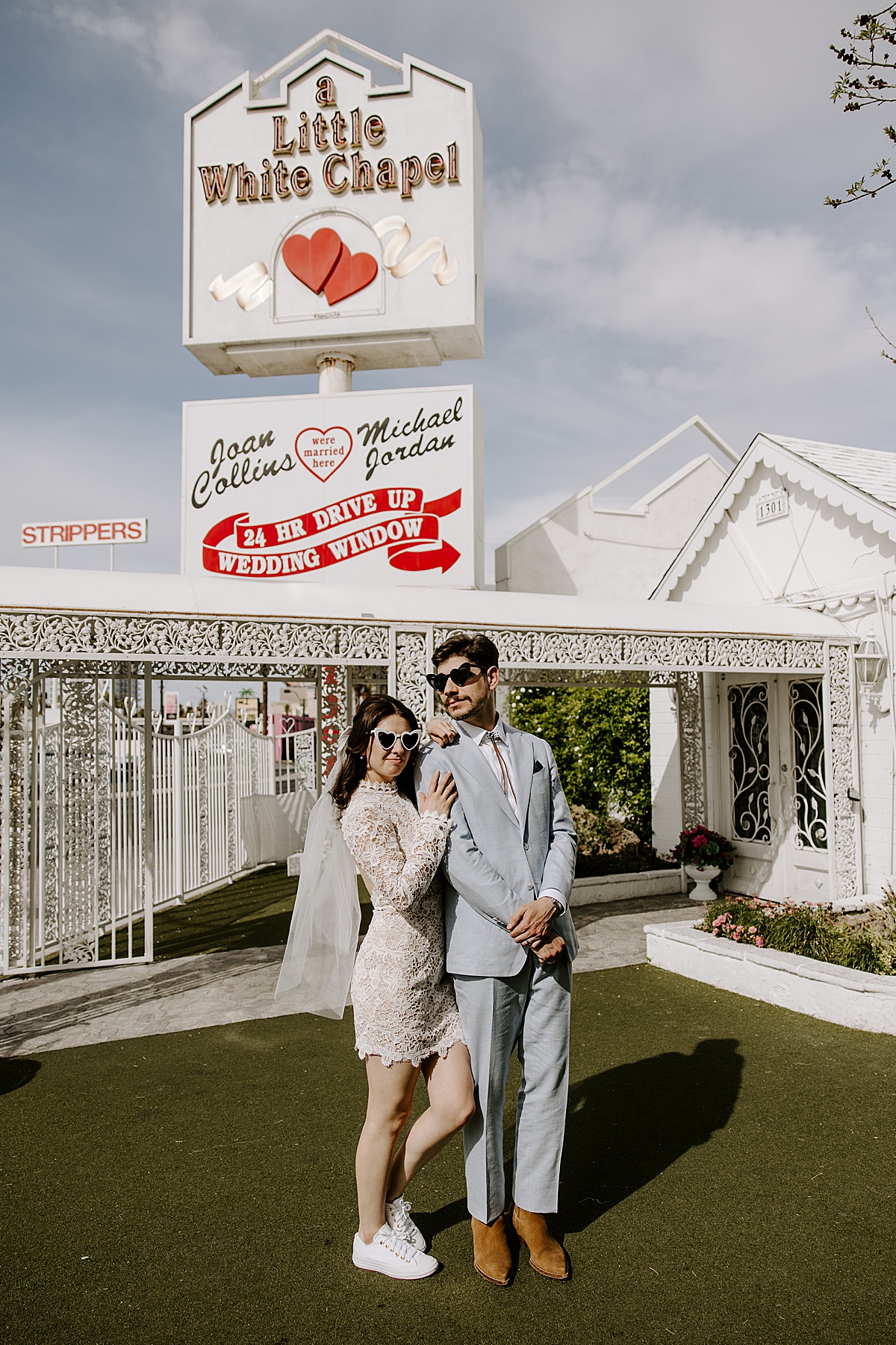 Newlyweds wear heart-shaped glasses and embrace one another by Katelyn Faye Photo