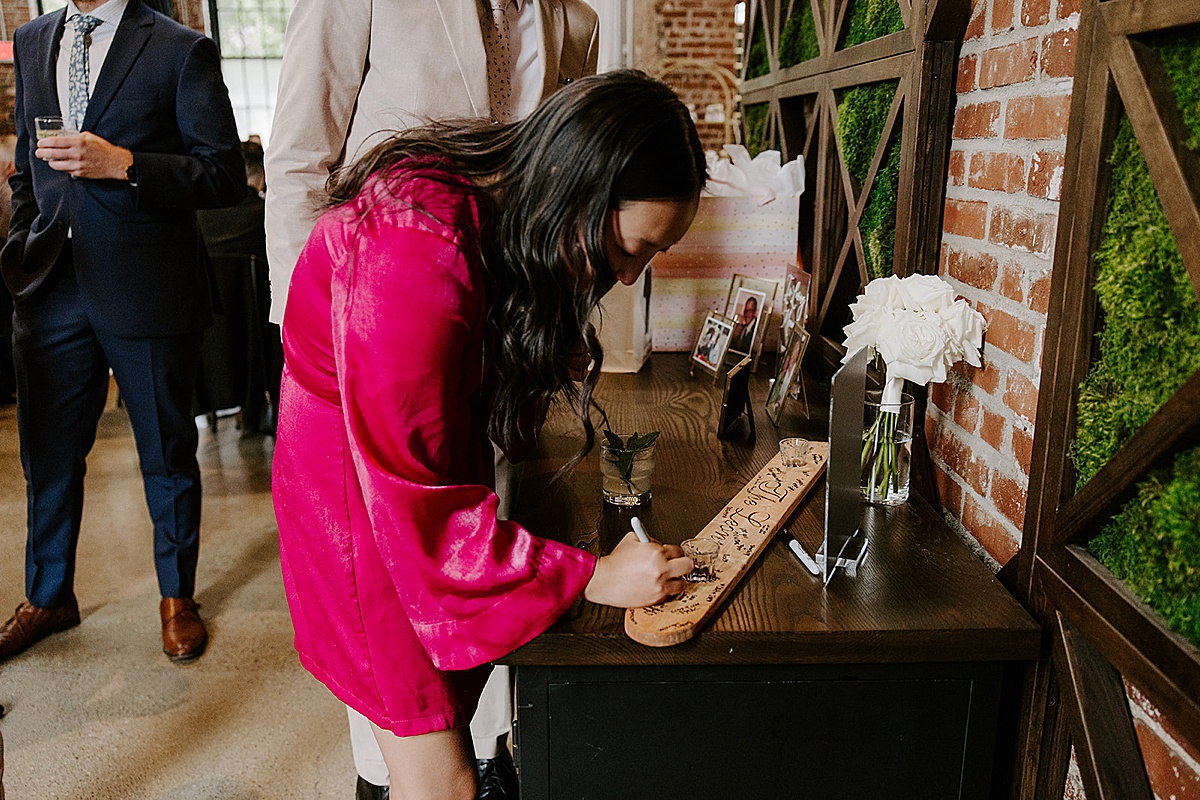 Guest in pink dress signs shot ski with a sharpie by Katelyn Faye Photography