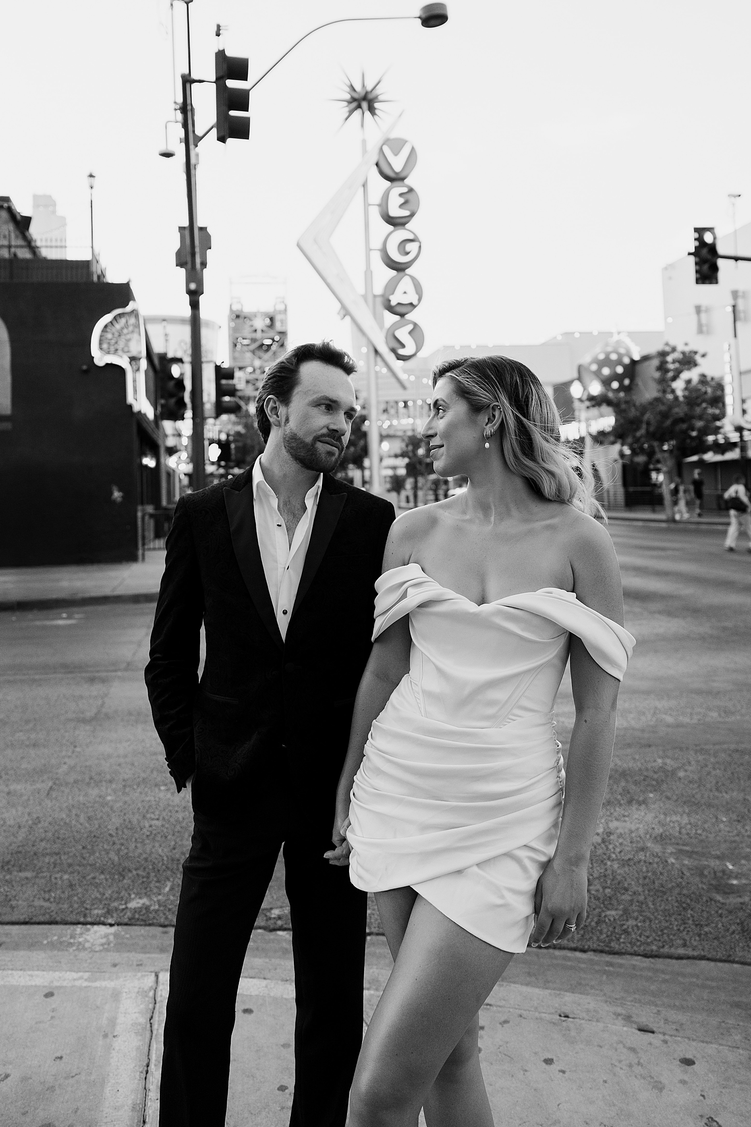 woman in white mini dress looks at her husband on street corner by Las Vegas Wedding Photographer