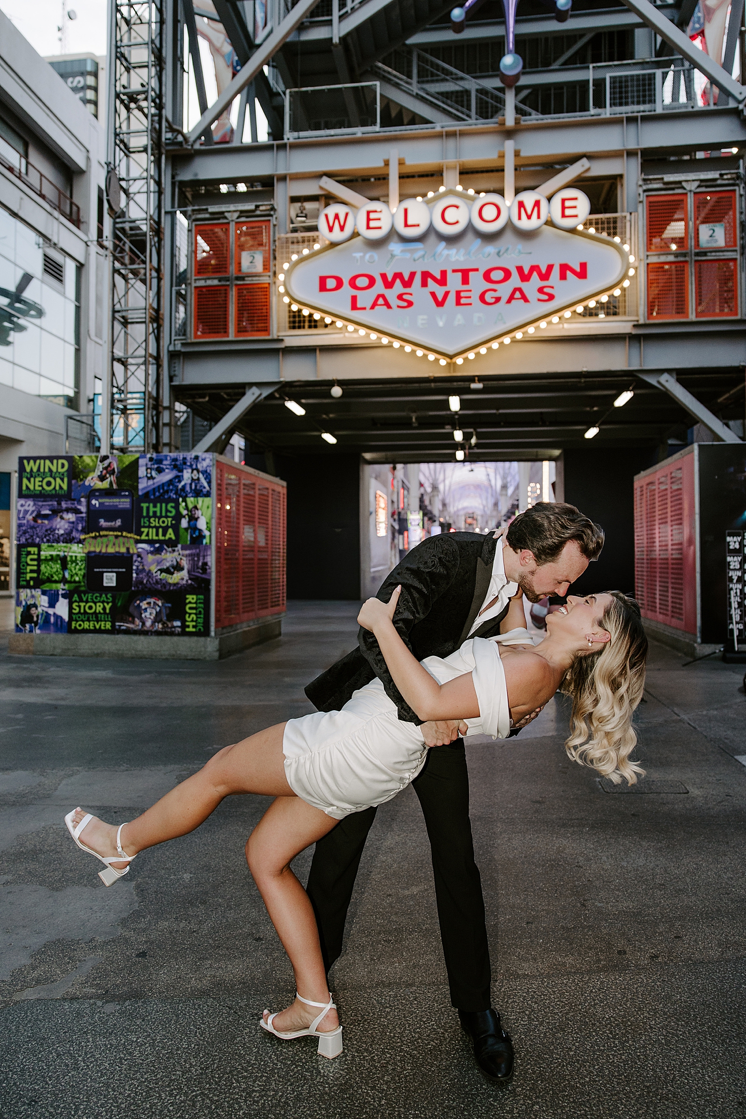 man dips his wife for a kiss in front of neon sign for Fremont Anniversary Session