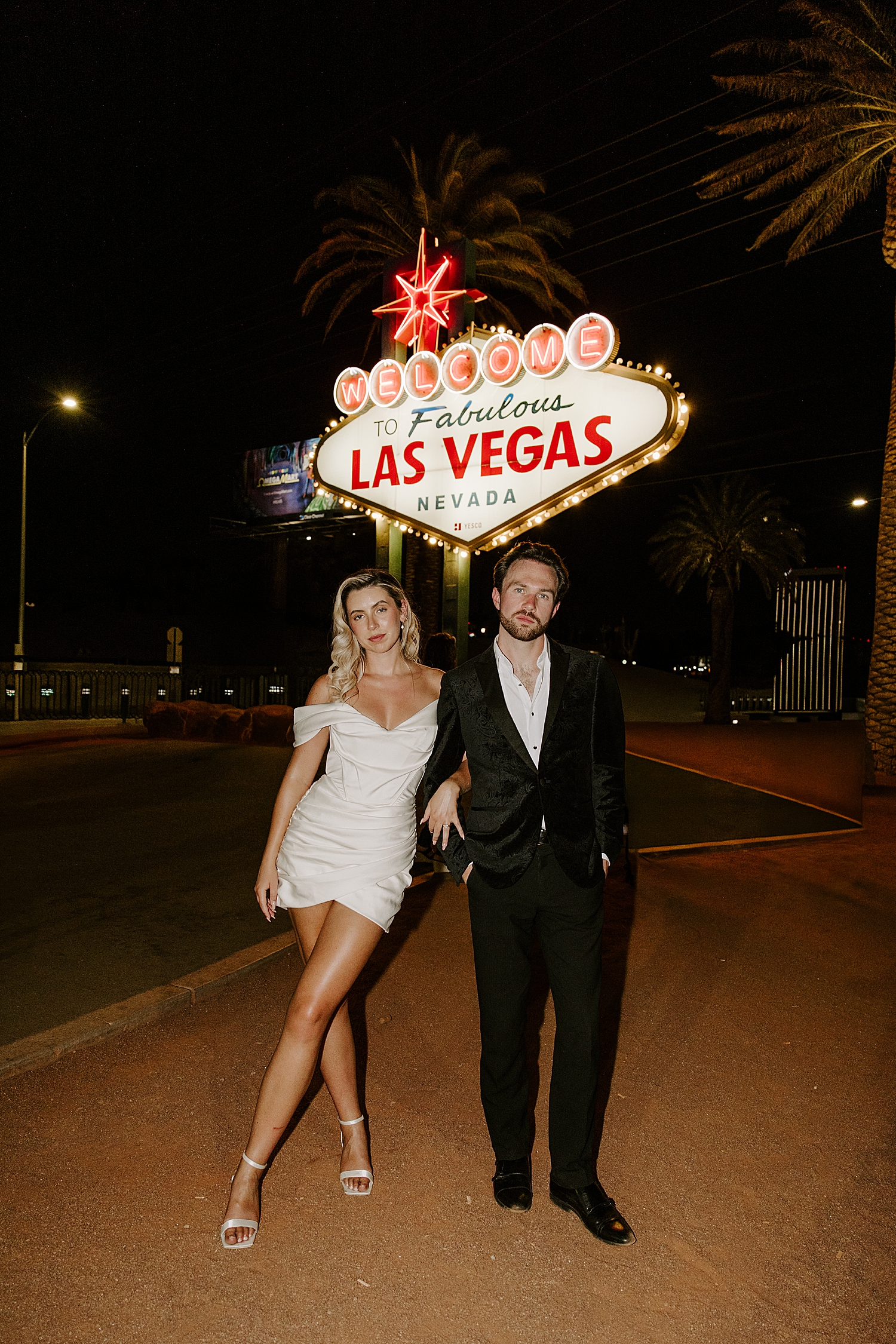 husband and wife stand under light up sign by Las Vegas Wedding Photographer