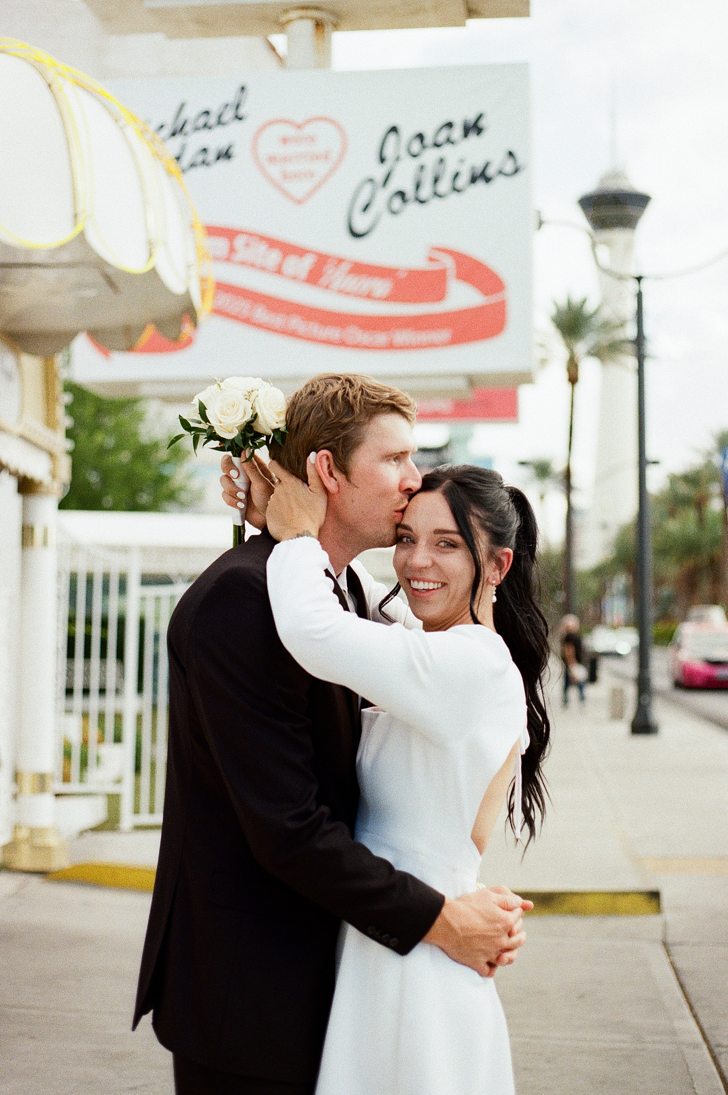 newlyweds embrace for a hug under chapel sign by Katelyn Faye Photography