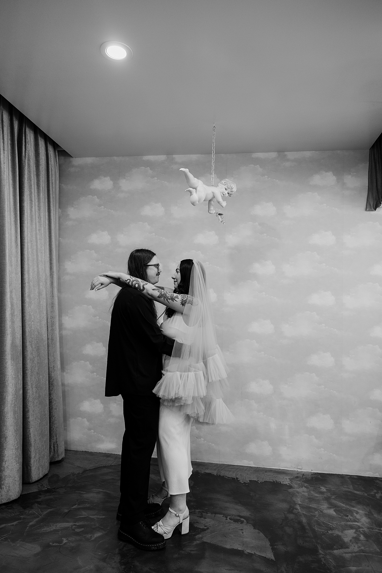 husband and wife stand under cherub together by Las Vegas wedding photographer