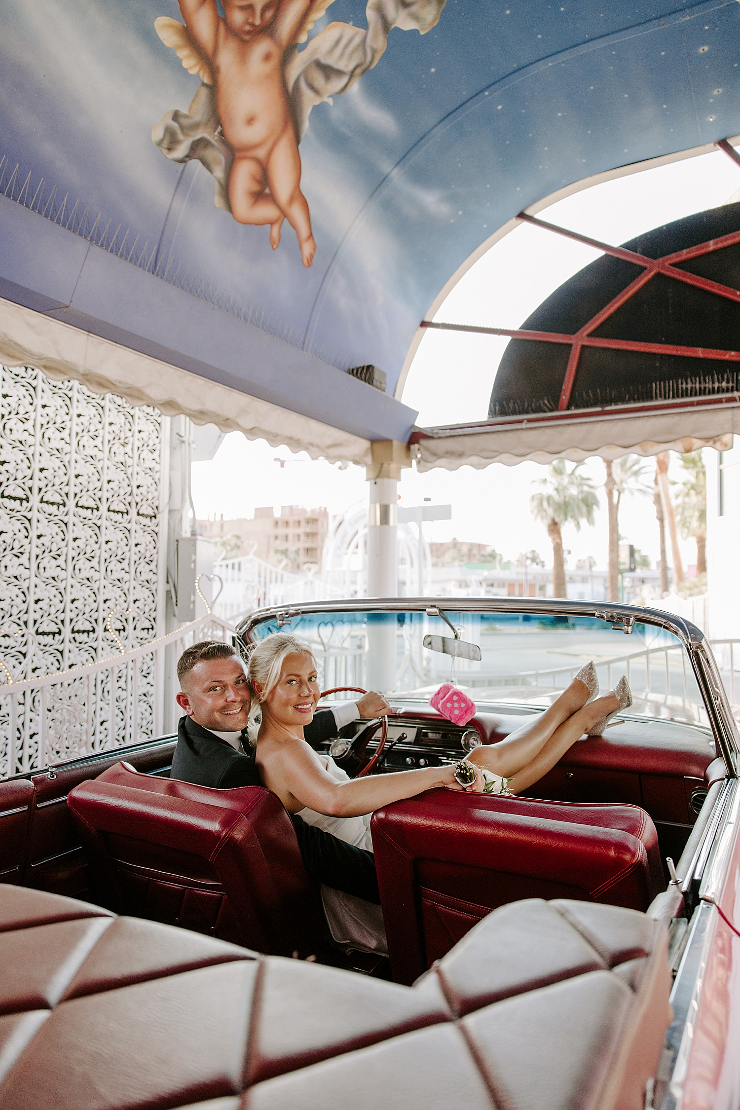Husband and wife lie back in pink corvette after ceremony in Tunnel of Love