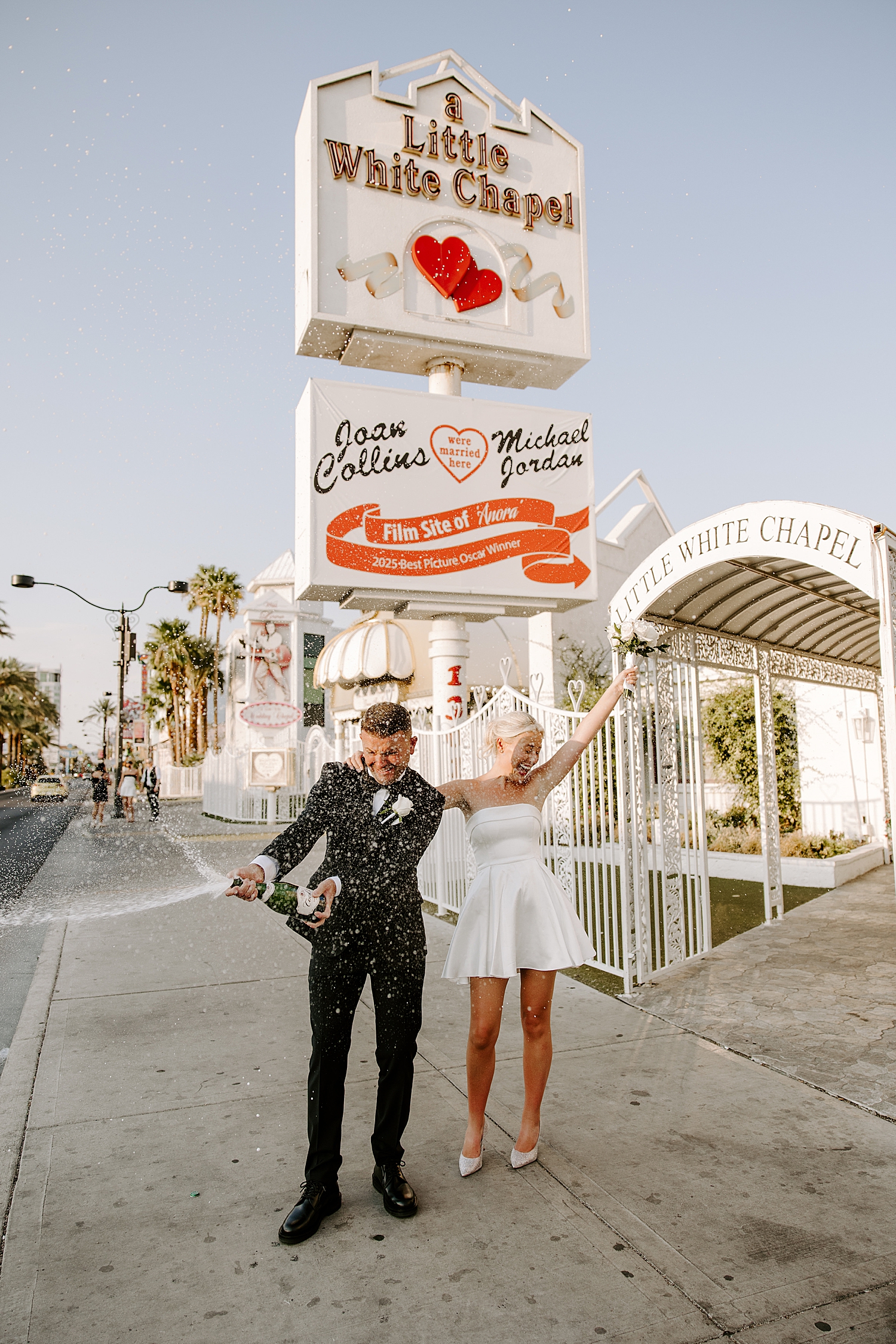 husband and wife pop champagne to celebrate at The Little White Chapel by Katelyn Faye Photography