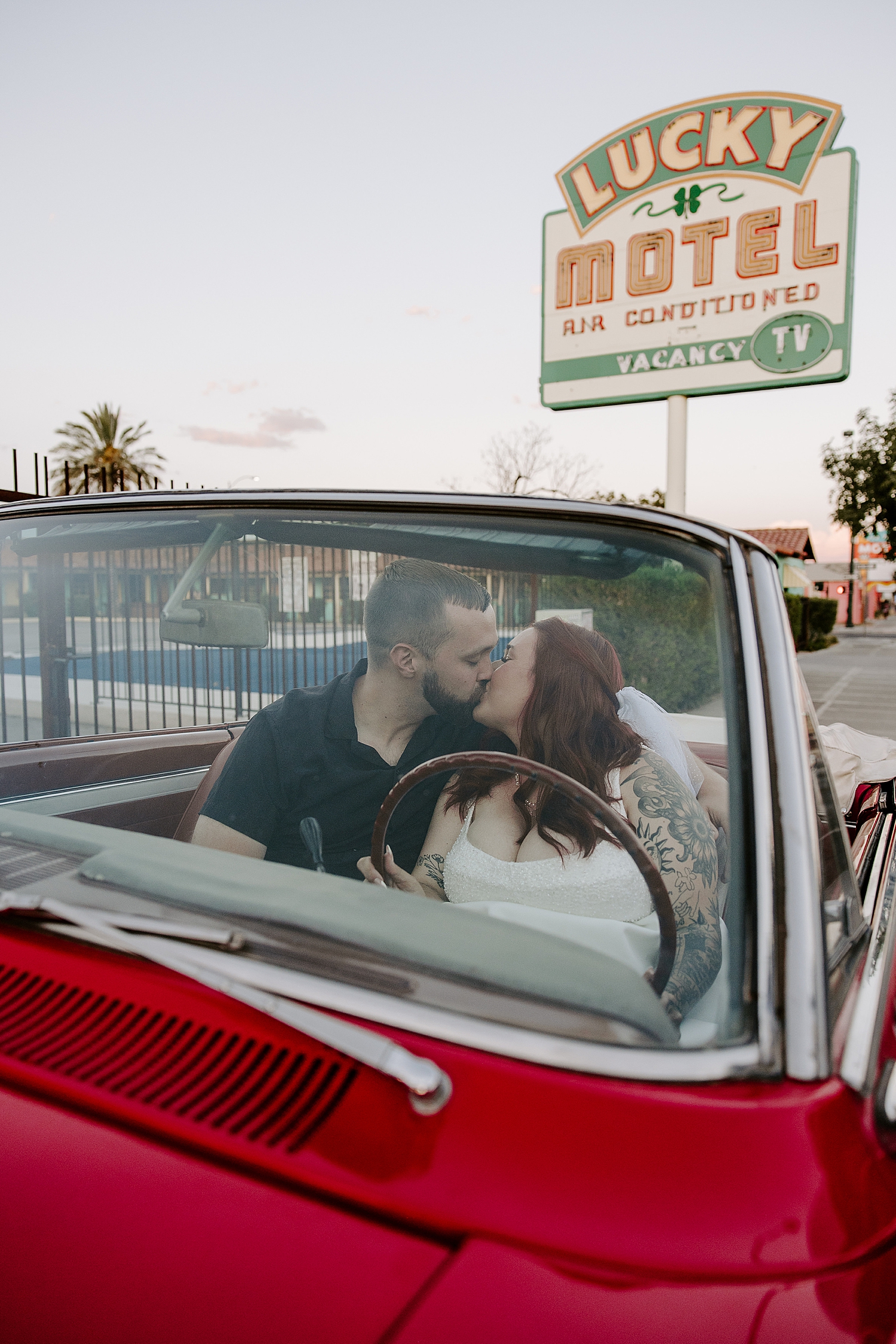 husband and wife share a sweet kiss in the front seat of vintage car