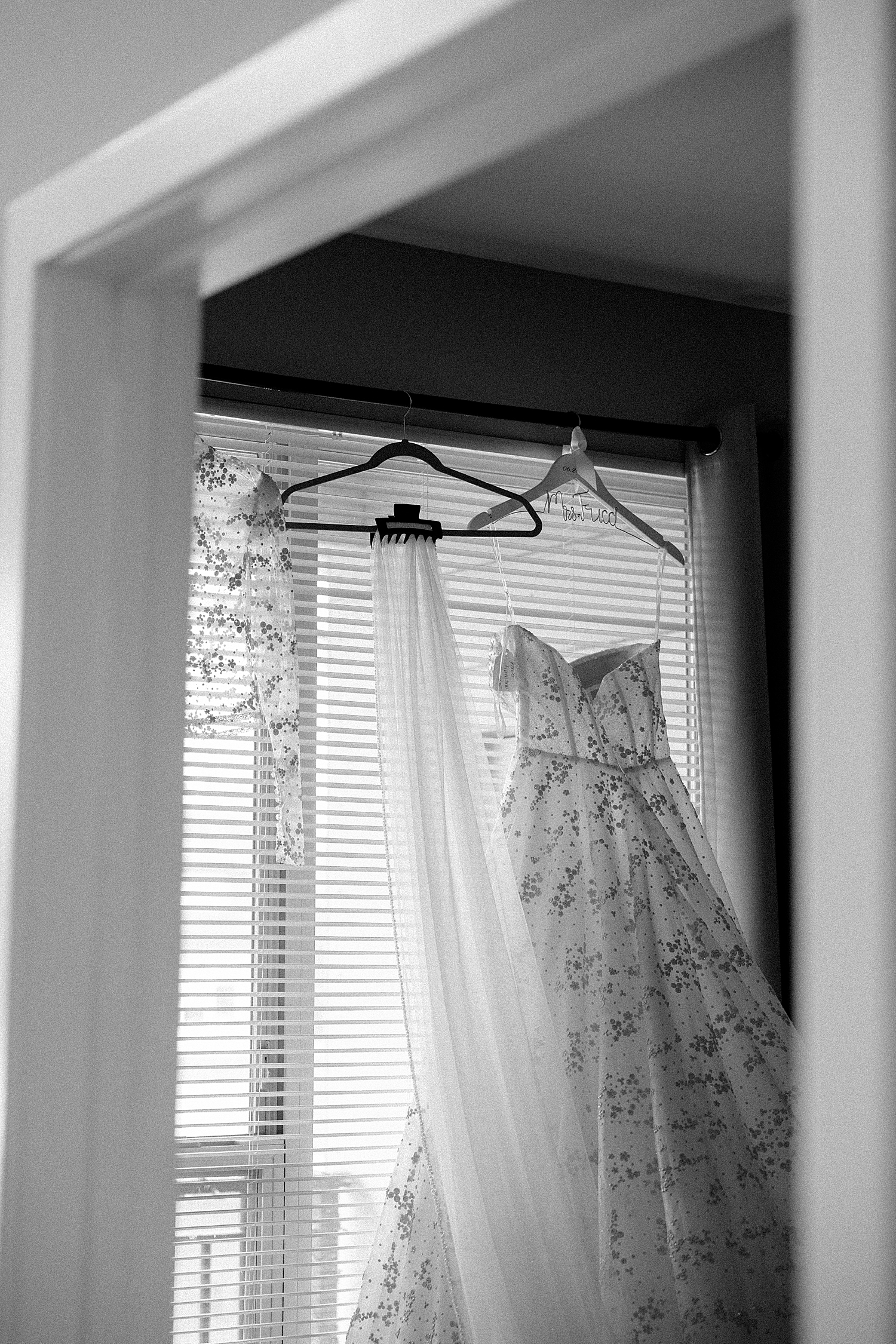 bridal gown with floral details hung in the window by Destination Photographer