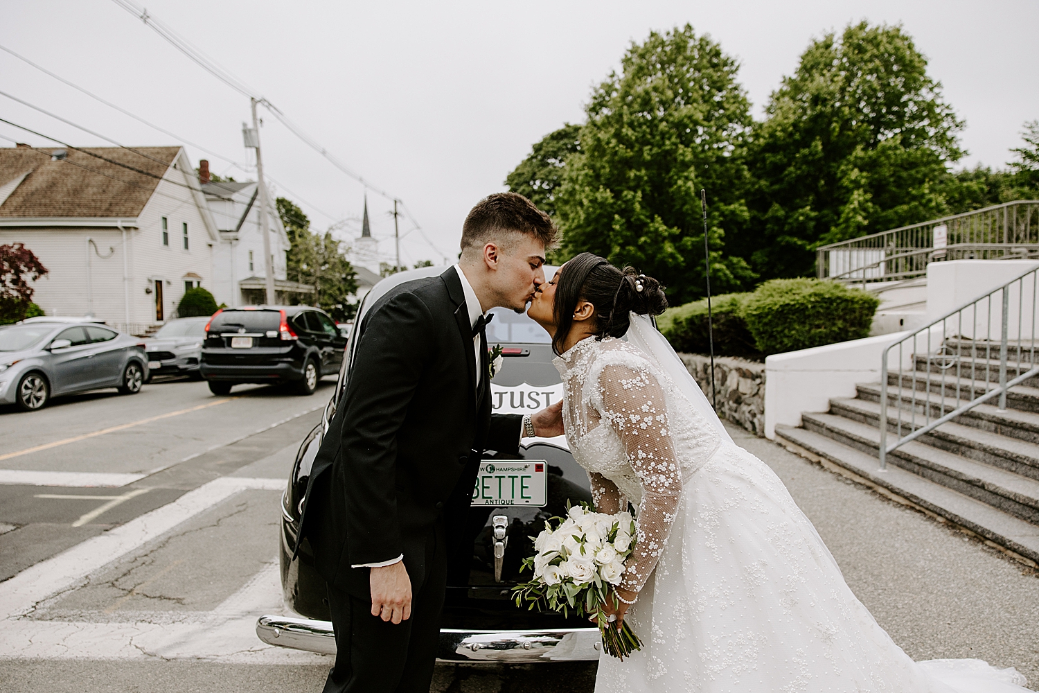 bride steals a kiss from her fiancé across the car at Boston Wedding