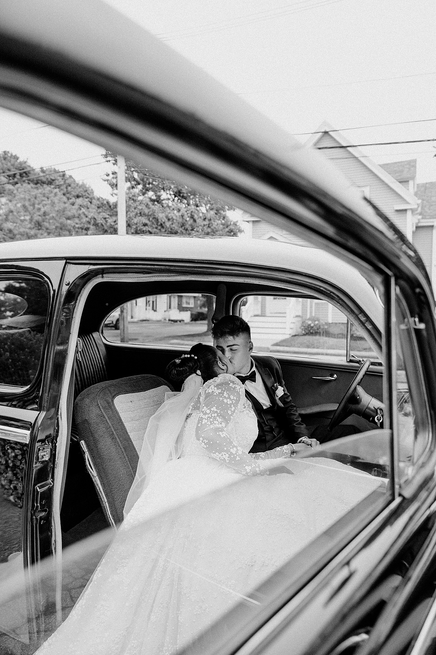 newlyweds steal a kiss in the back of old timey car by Destination Photographer