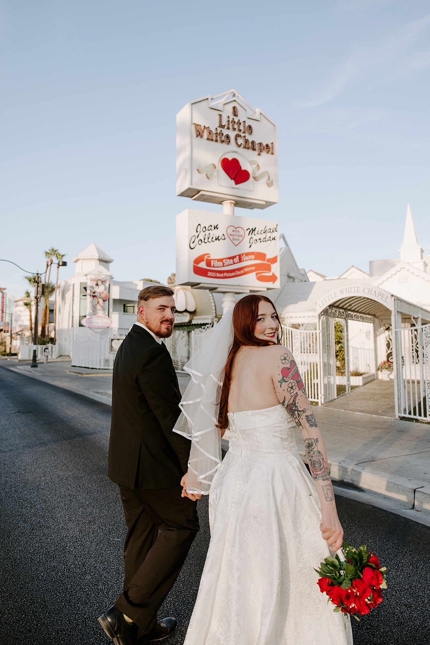 redhead bride looks over her should outside of the Little White Chapel by Las Vegas wedding photographer