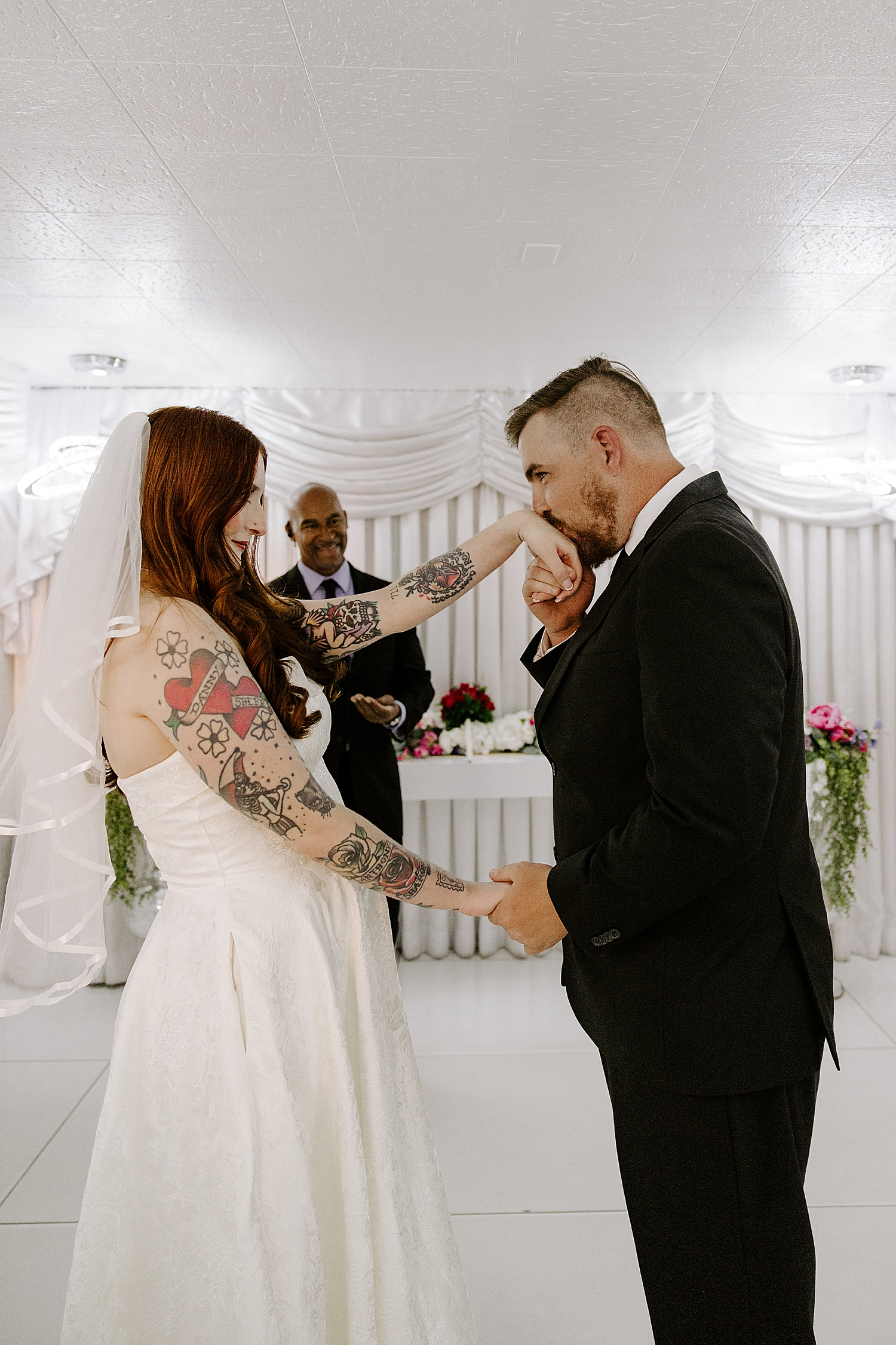 man kisses his bride's hands during ceremony at LWC by Las Vegas wedding photographer