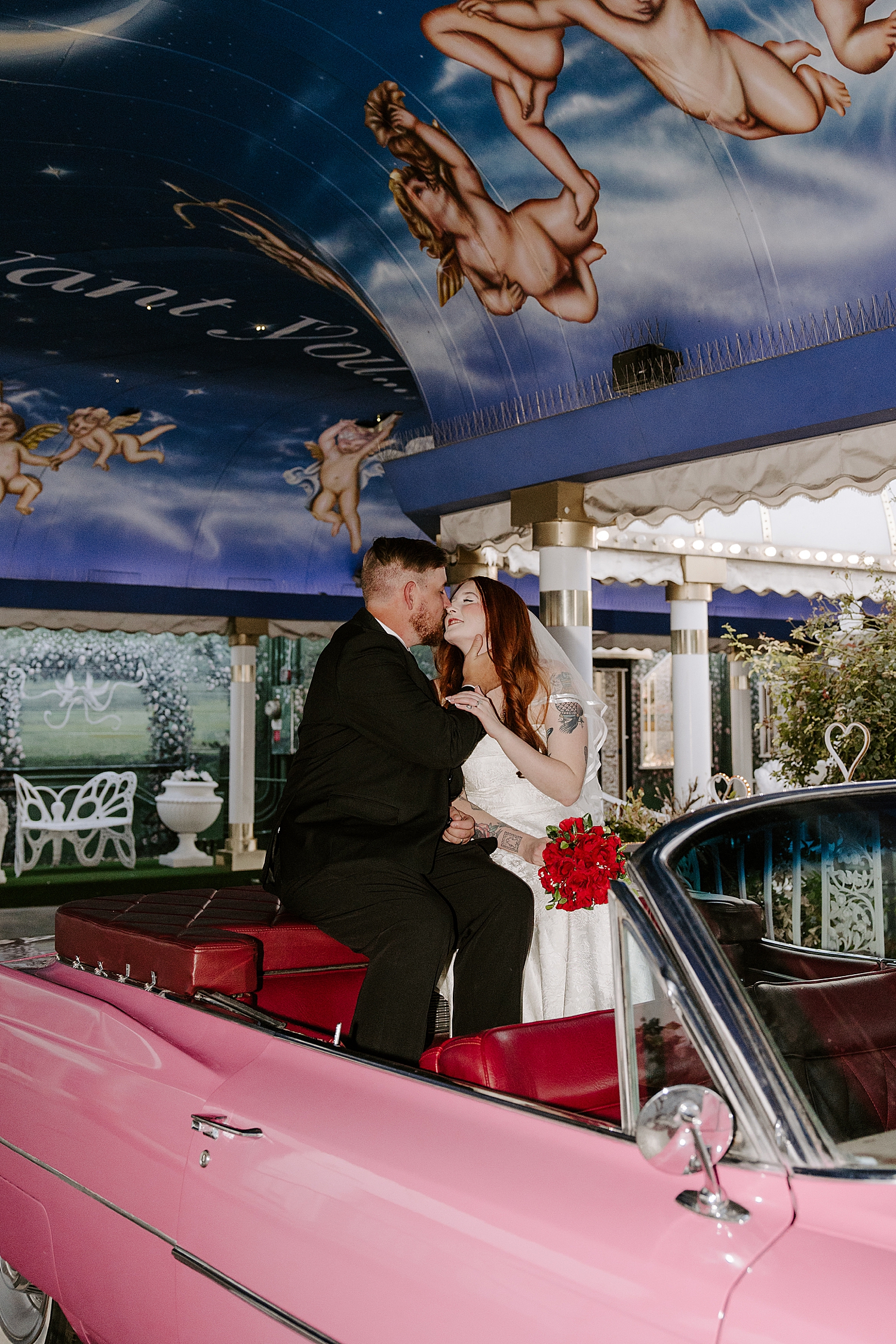 newlyweds sit on top of a pink corvette by Las Vegas wedding photographer