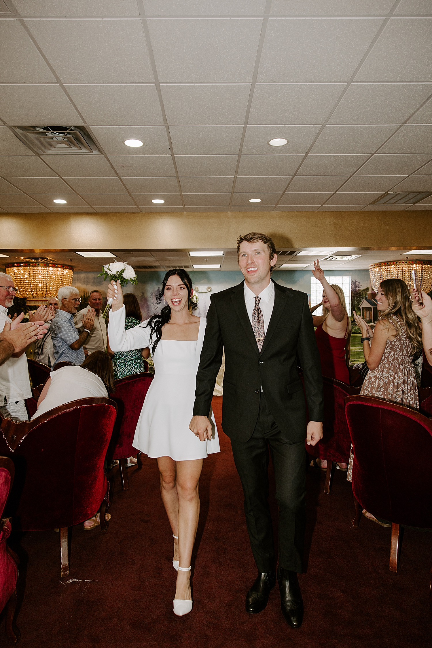 man and woman walk down aisle at little White chapel after learning 5 most asked questions about eloping in Las Vegas