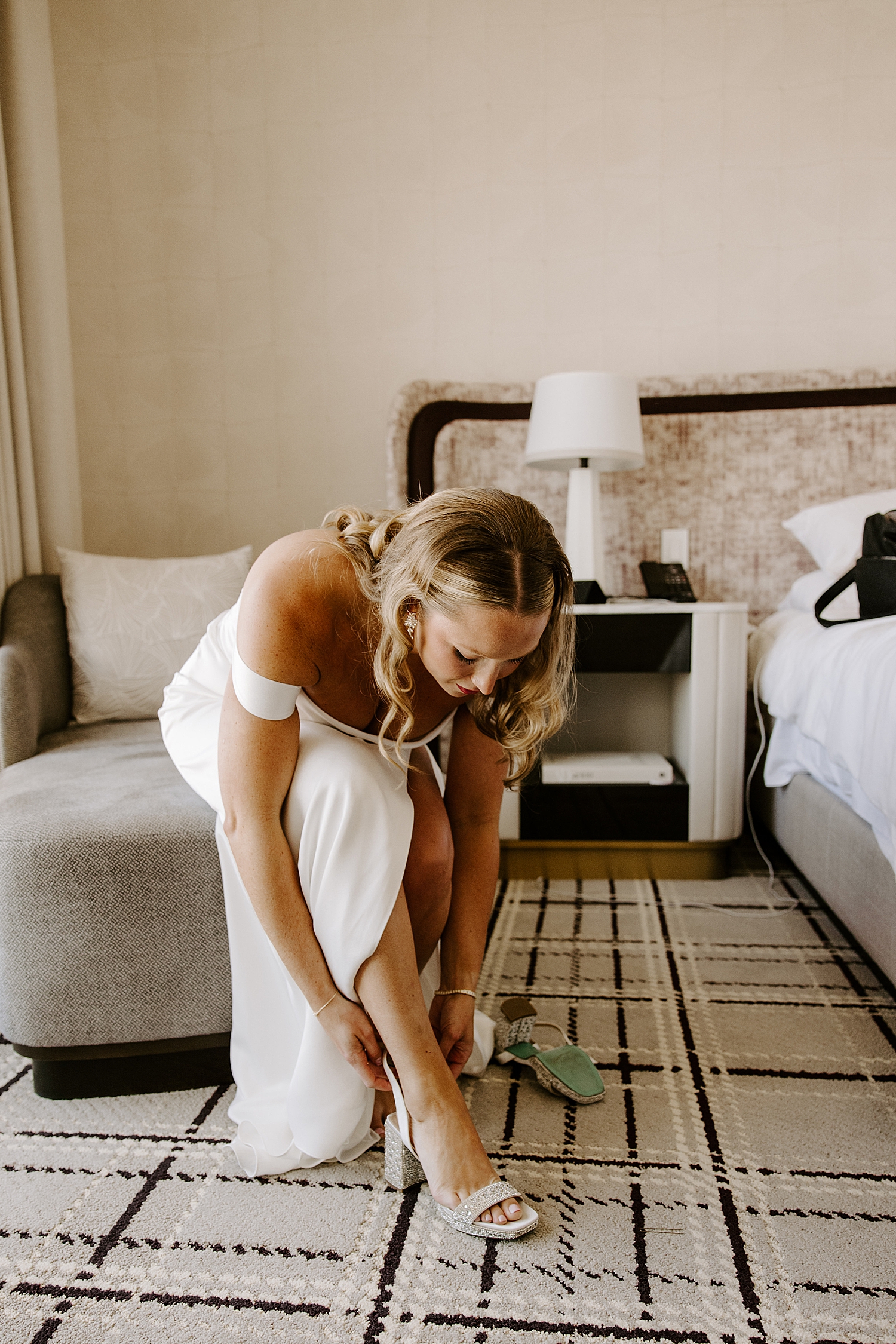 bride adjusts her sandals in hotel room by Las Vegas wedding photographer
